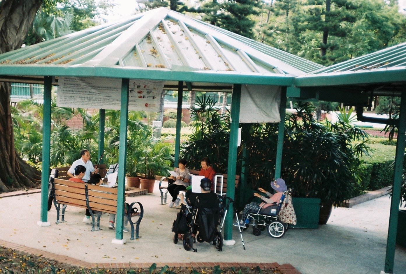 covered bench and strollers in a green garden rest area