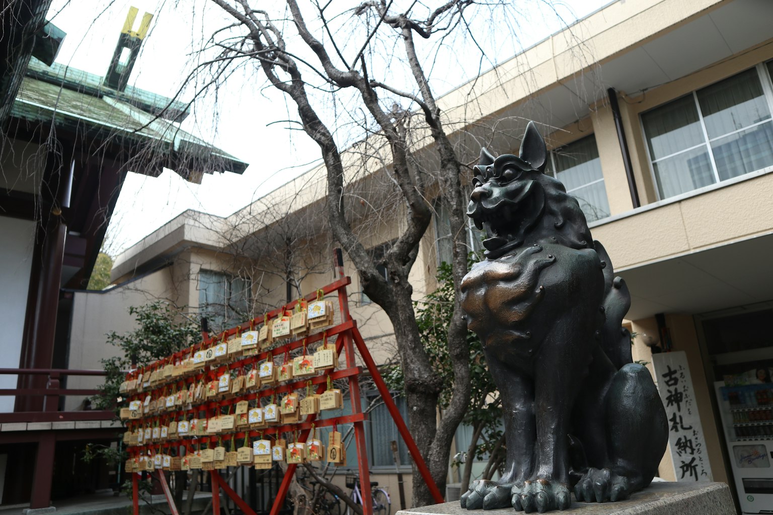 神社前的黑色狛犬雕像和树木
