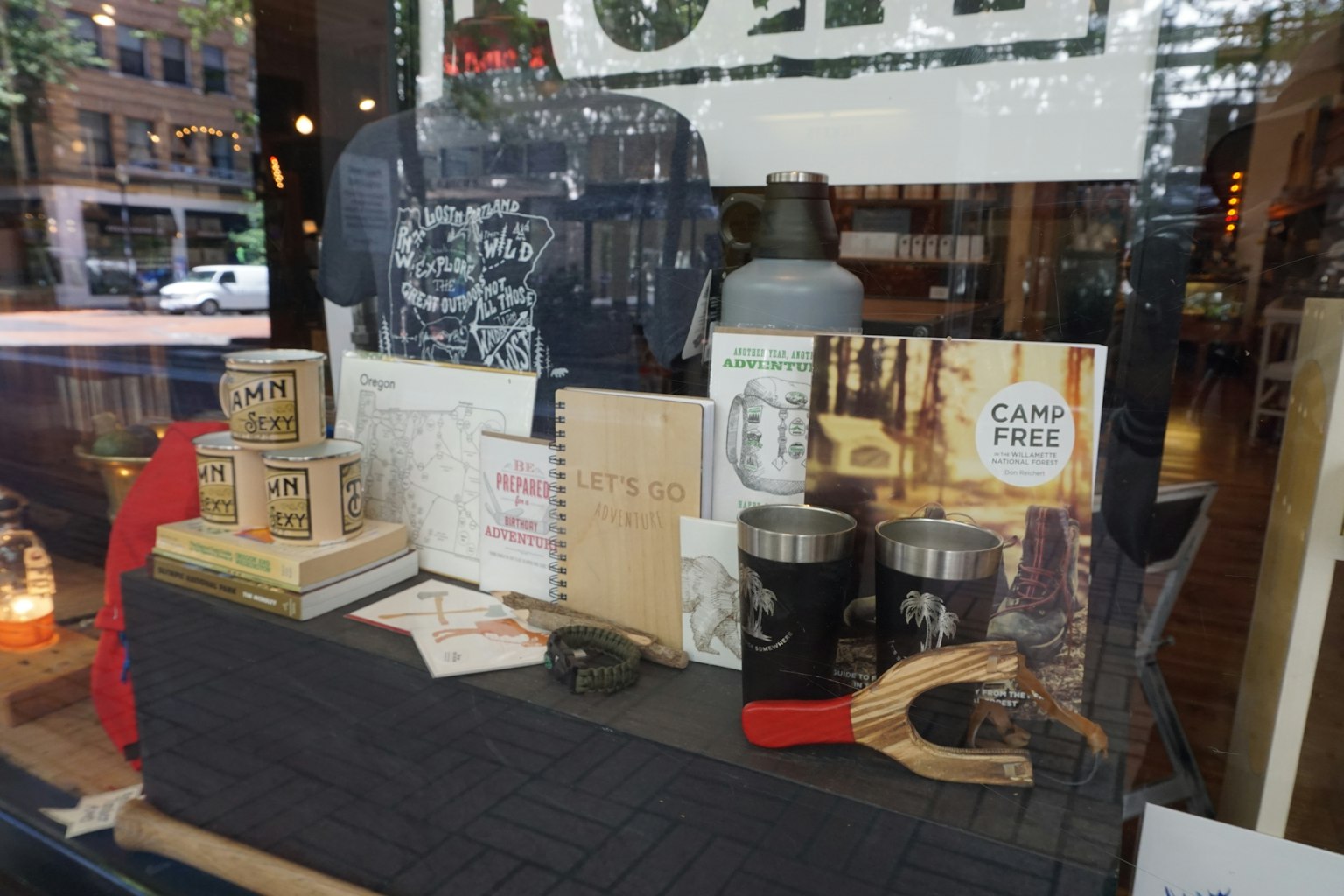 商店櫥窗展示各種商品包括背包 筆記本 杯子和露營裝備
