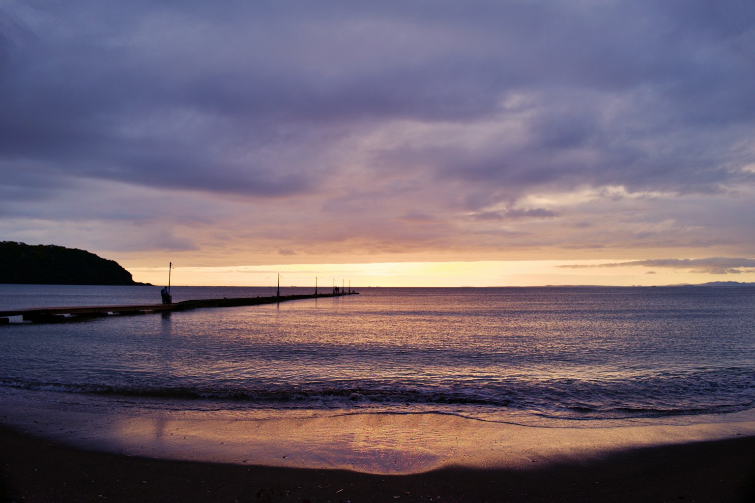 Tramonto viola su una costa con un molo