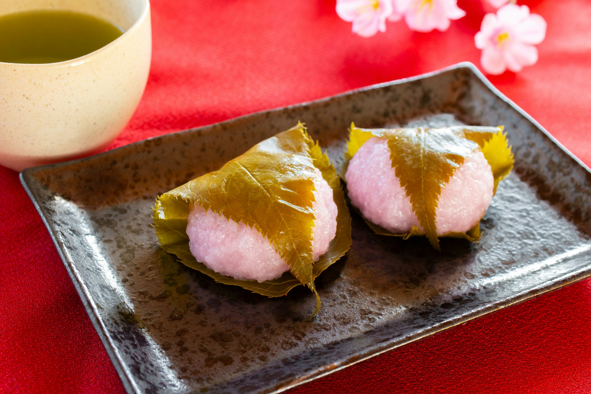 sakura mochi sobre una tela roja con té verde