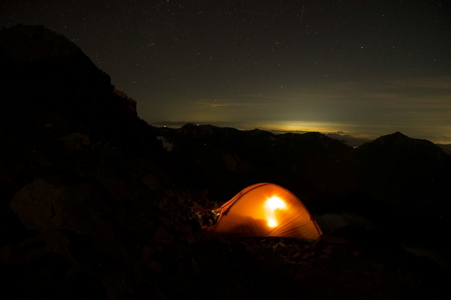 Tenda luminosa nelle montagne sotto un cielo stellato