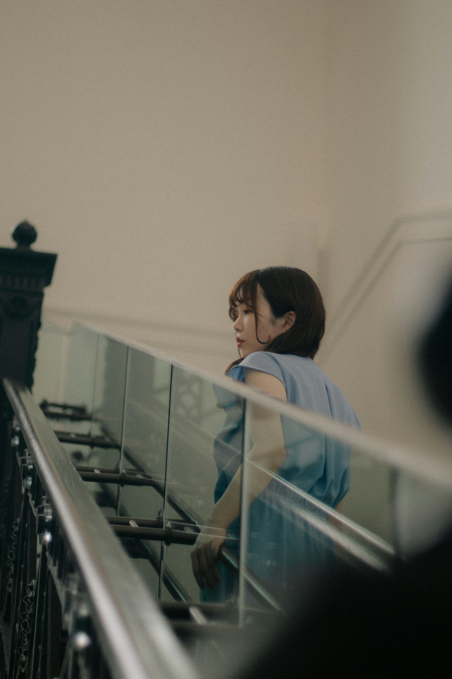 Eine Frau in einem hellblauen Outfit, die die Treppe hinaufgeht