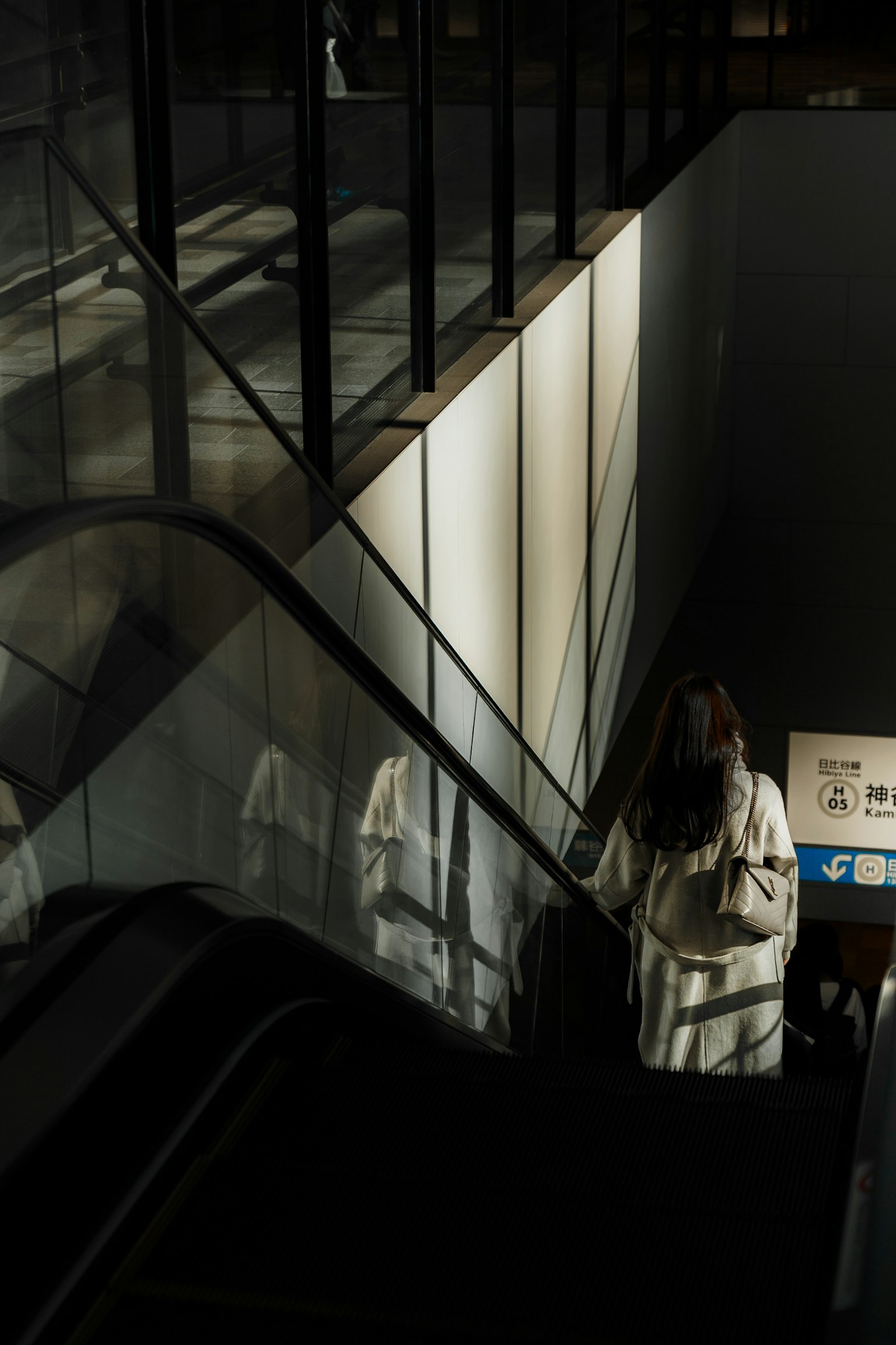 一名女性在现代空间中下楼梯，周围有玻璃元素