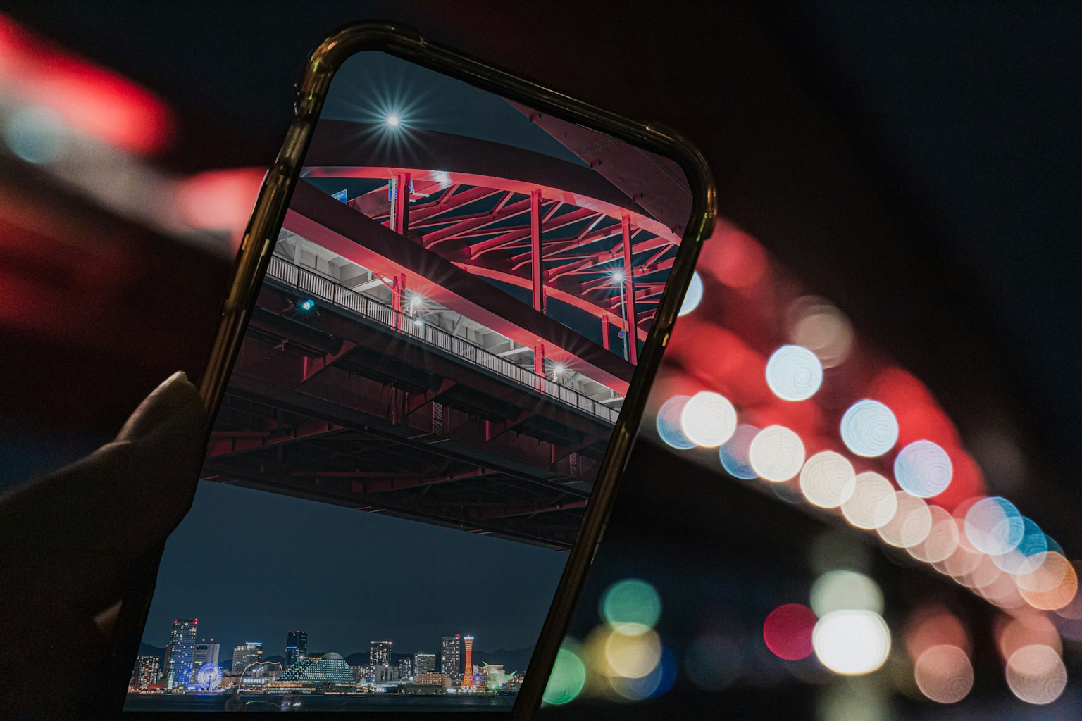 Bild eines Smartphones, das eine nächtliche Aussicht unter einer roten Brücke aufnimmt