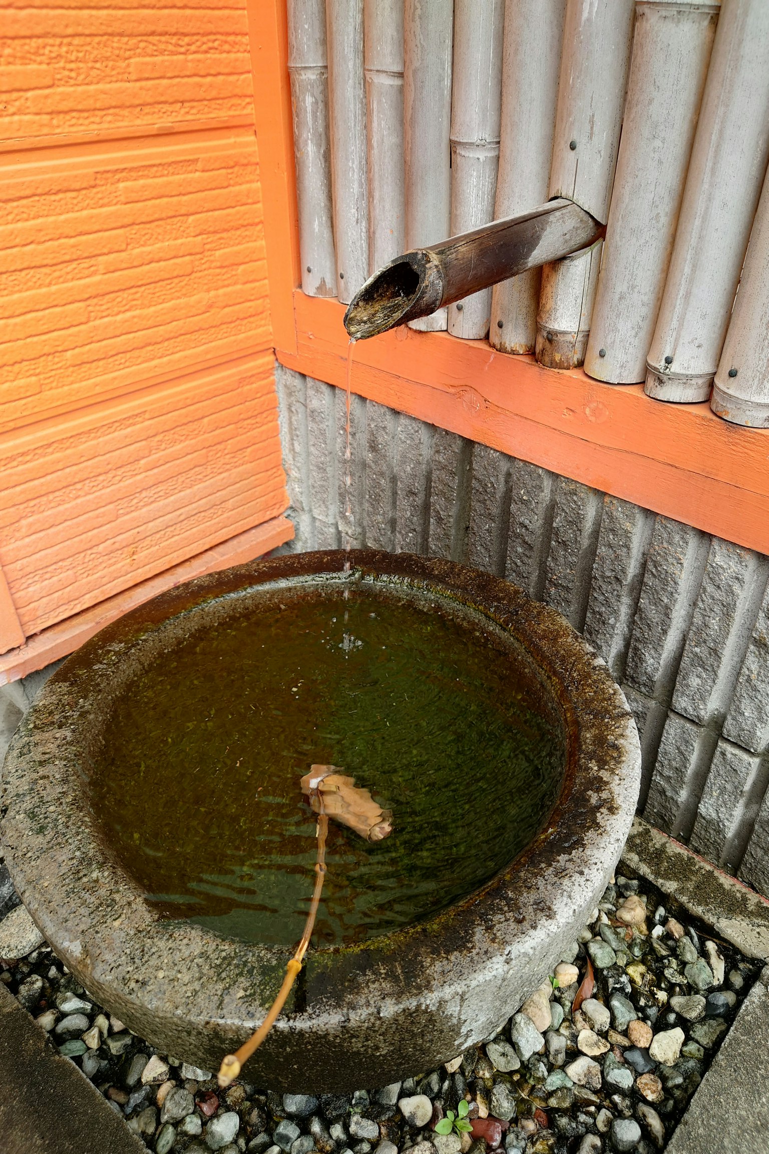 Steinbecken mit fließendem Wasser und Bambusauslauf