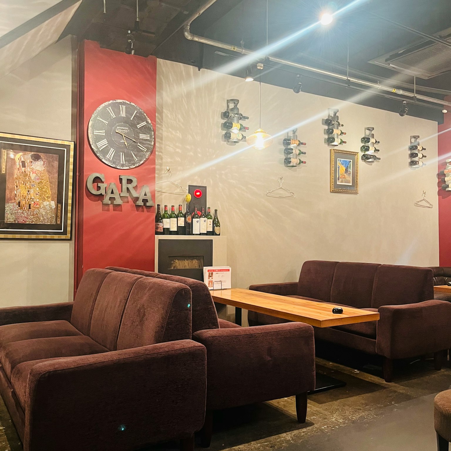 Intérieur de café confortable avec des canapés marron et des tables en bois présentant une horloge et des œuvres d'art sur le mur