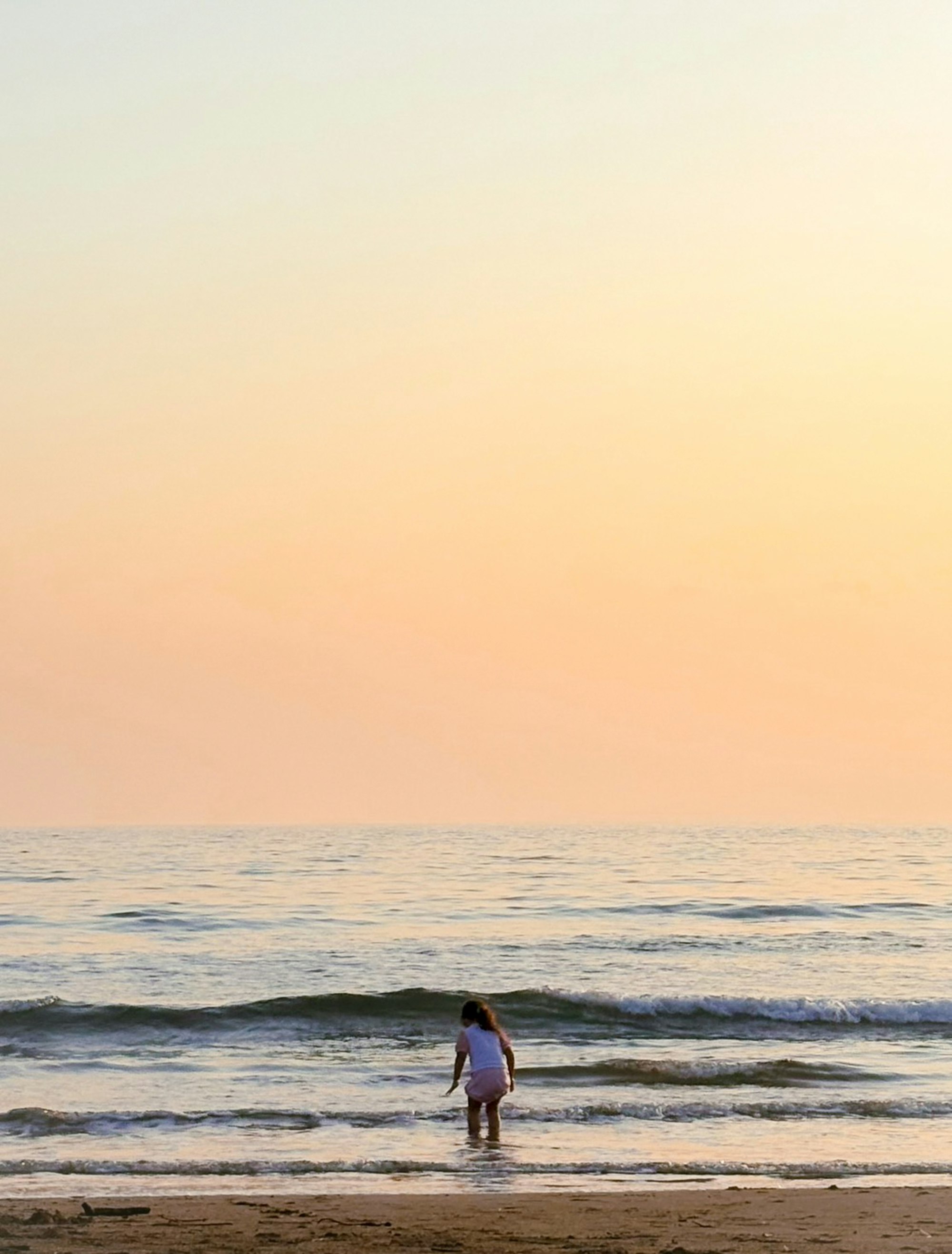 夕暮れの海辺で歩く人の後ろ姿