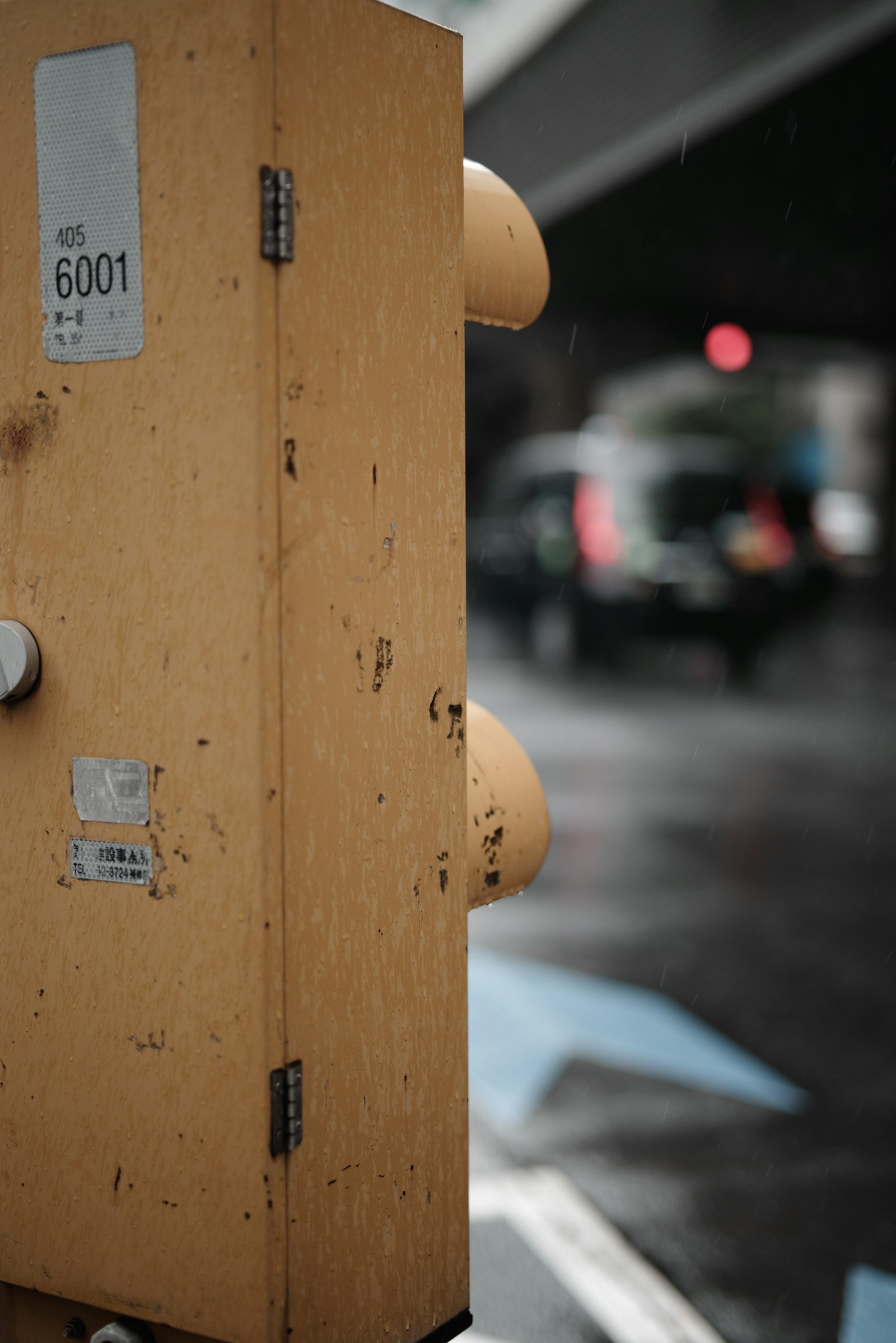 Seitenansicht einer gelben Ampel mit verschwommenen Autos und einem roten Signal im Hintergrund