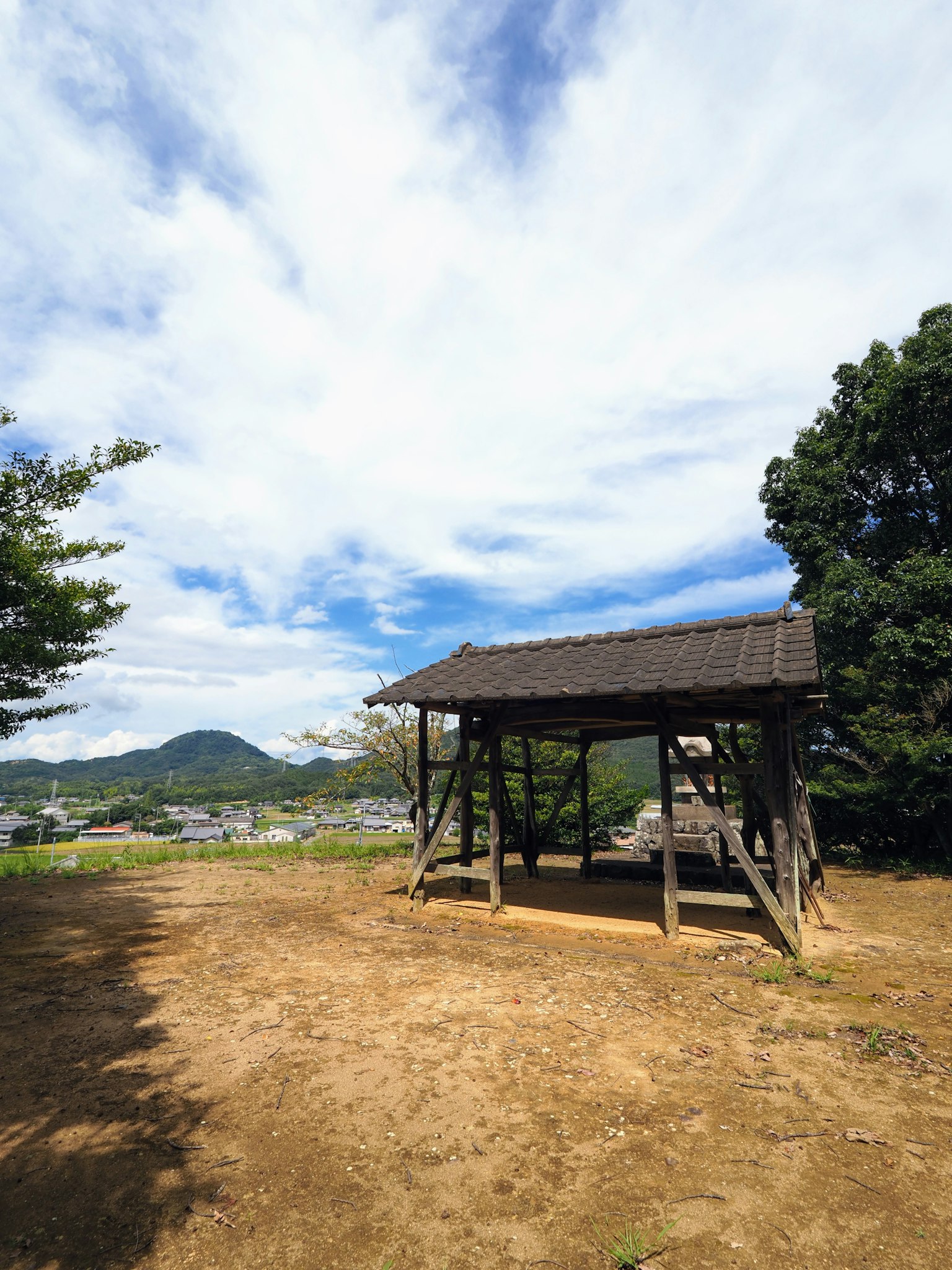 Holzhütte unter blauem Himmel mit verstreuten Wolken und grüner Umgebung