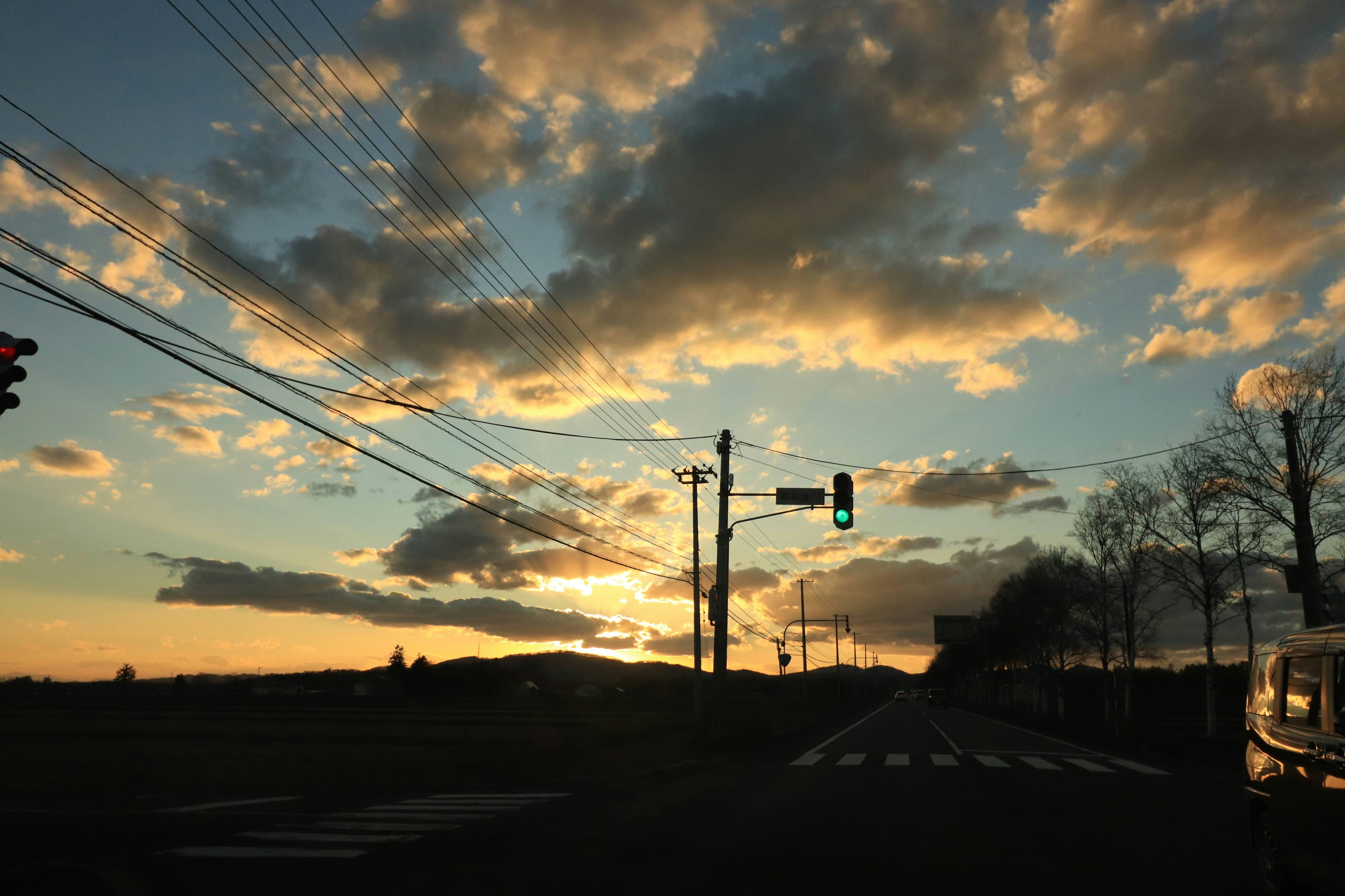 夕暮れの郊外道路を走る車と信号のある交差点