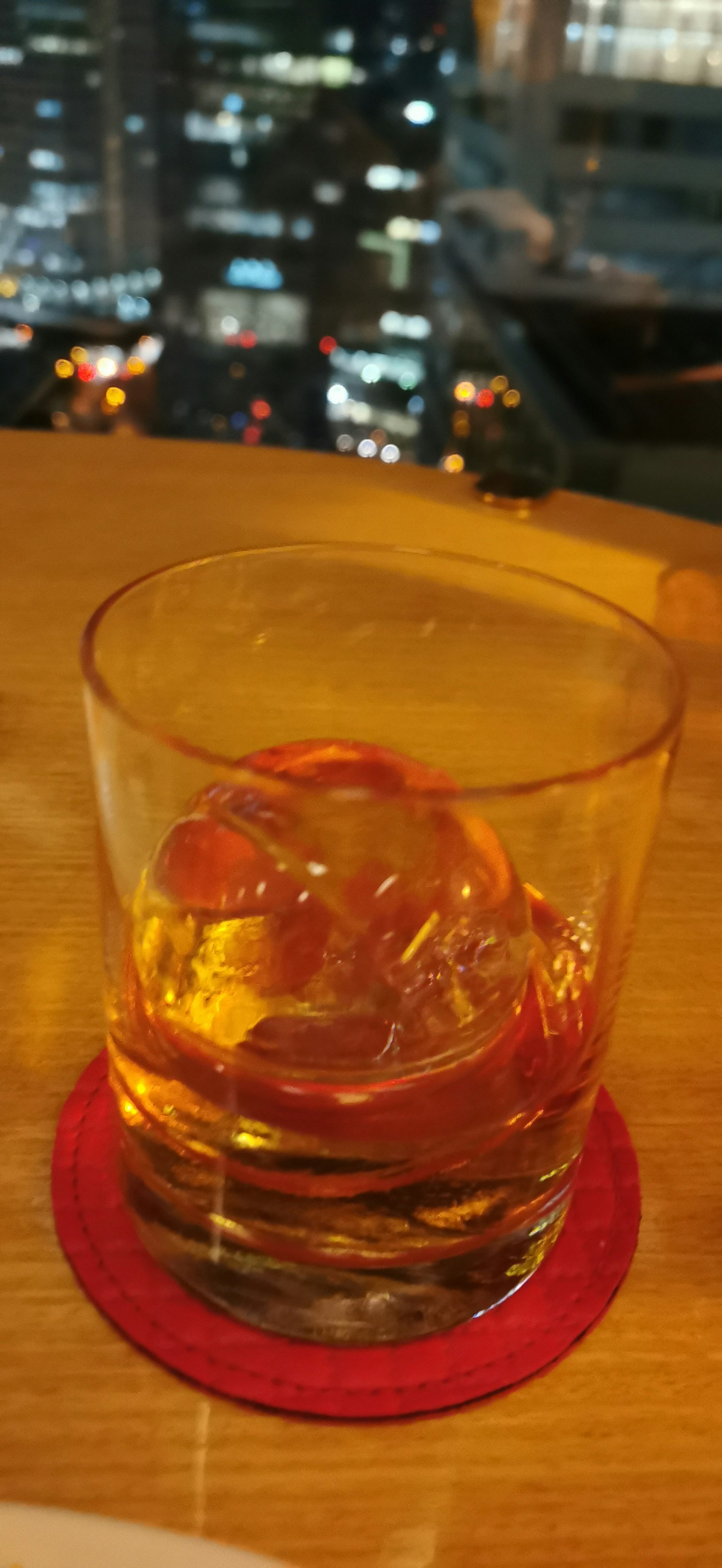 도시 스카이라인을 배경으로 한 얼음이 담긴 위스키 잔