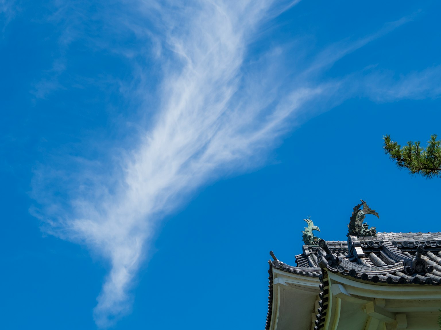 Nuvole in un cielo blu con parte del tetto di un edificio tradizionale