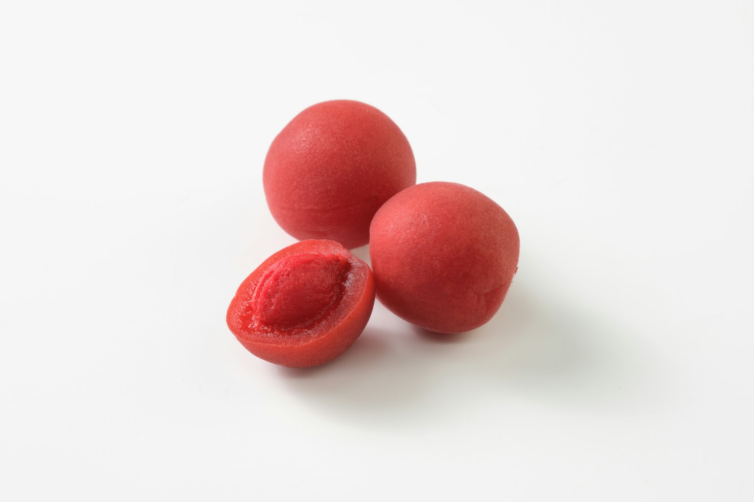 Tres objetos esféricos rojos, uno cortado por la mitad