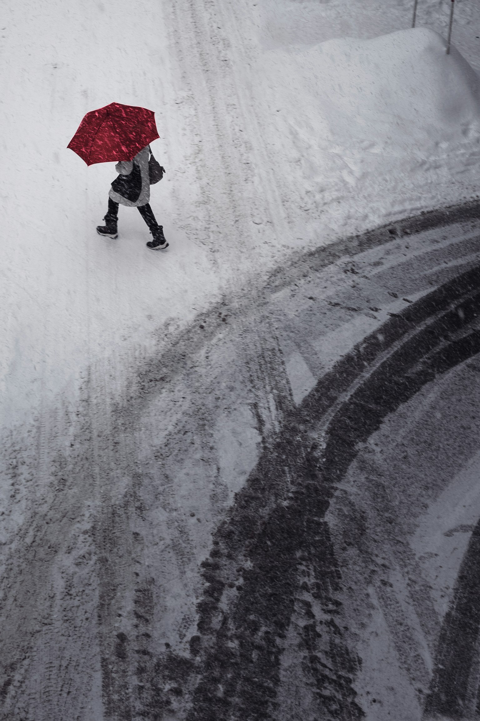 Person, der im Schnee mit einem roten Regenschirm geht