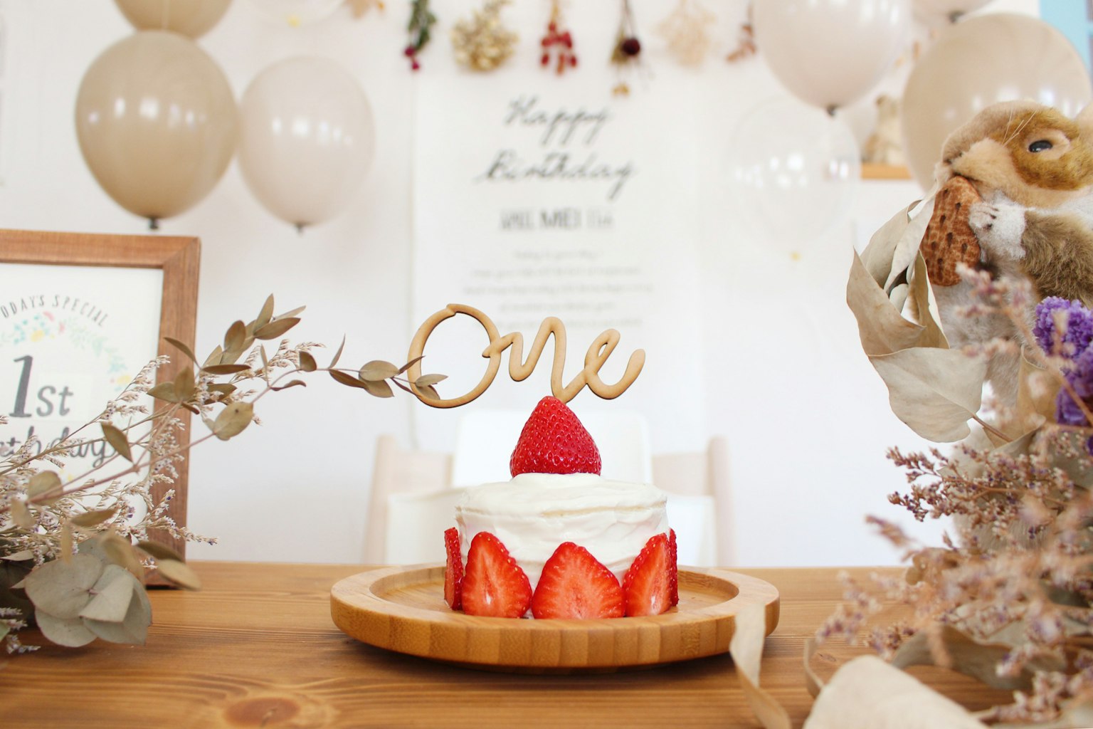 Gâteau à la fraise avec un topper 'One' sur une table d'anniversaire