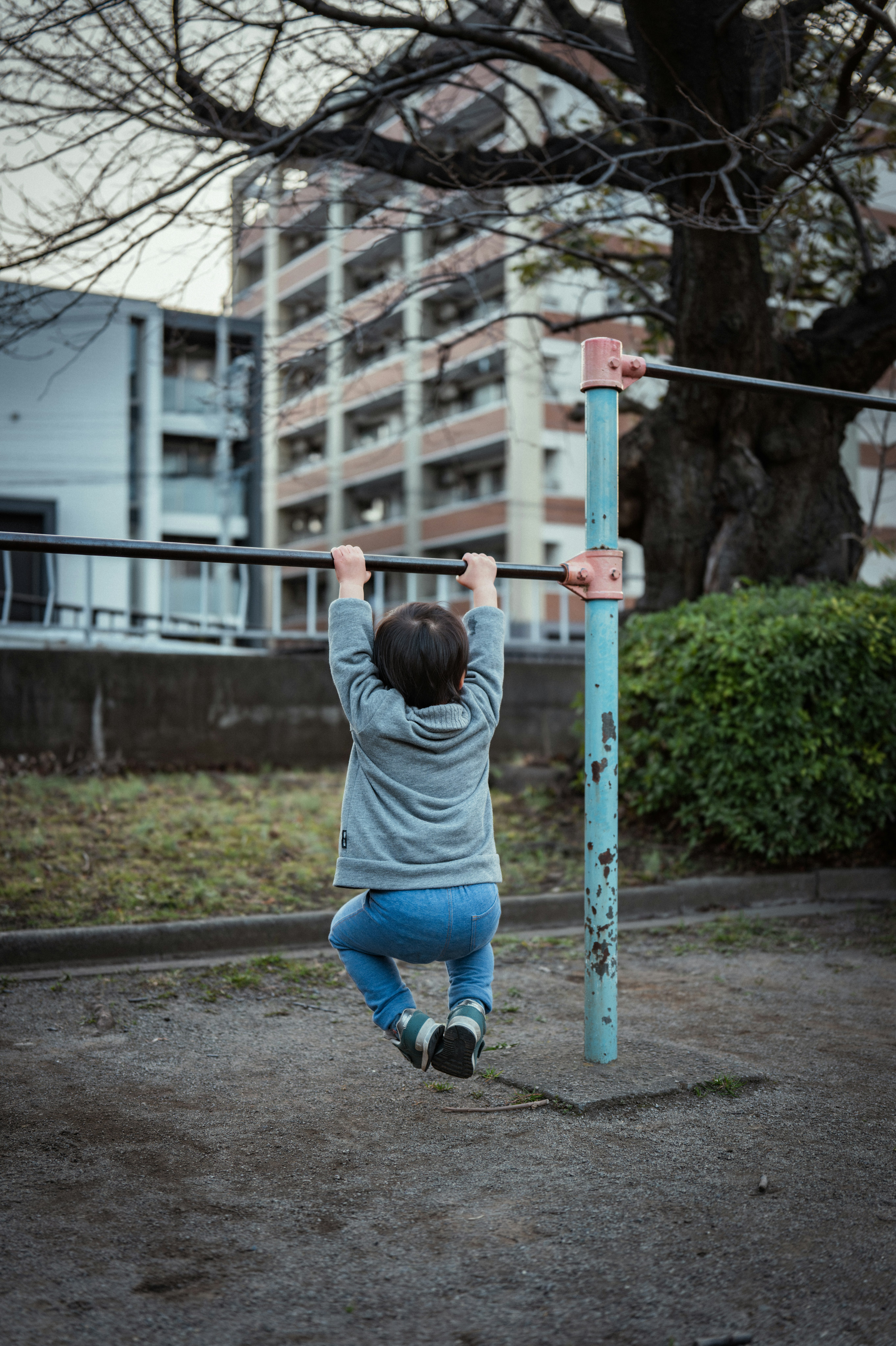 鉄棒を掴んで遊ぶ子どものいる近所の公園