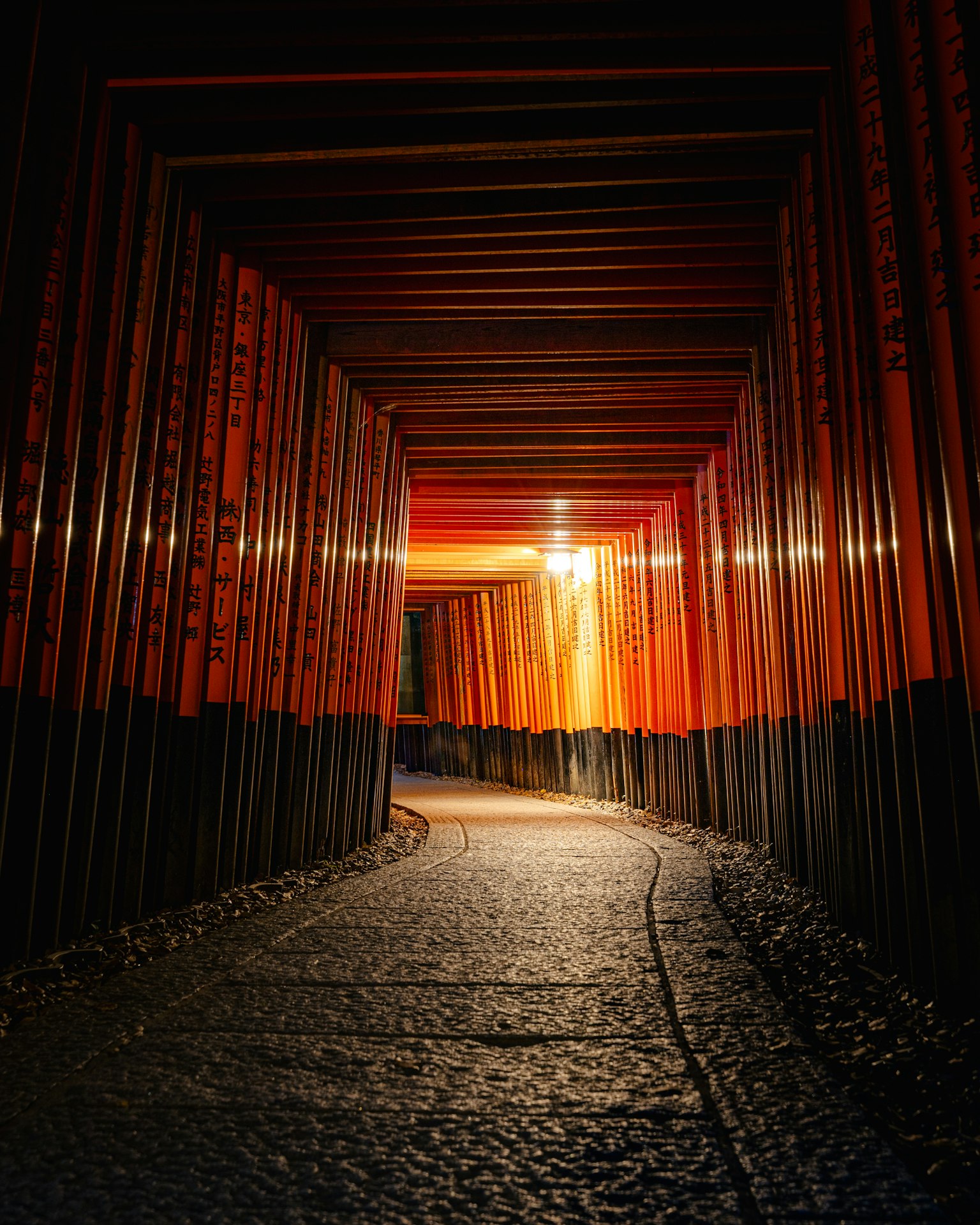 Interno di un tunnel buio con pareti di legno rosso e un sentiero in ciottoli