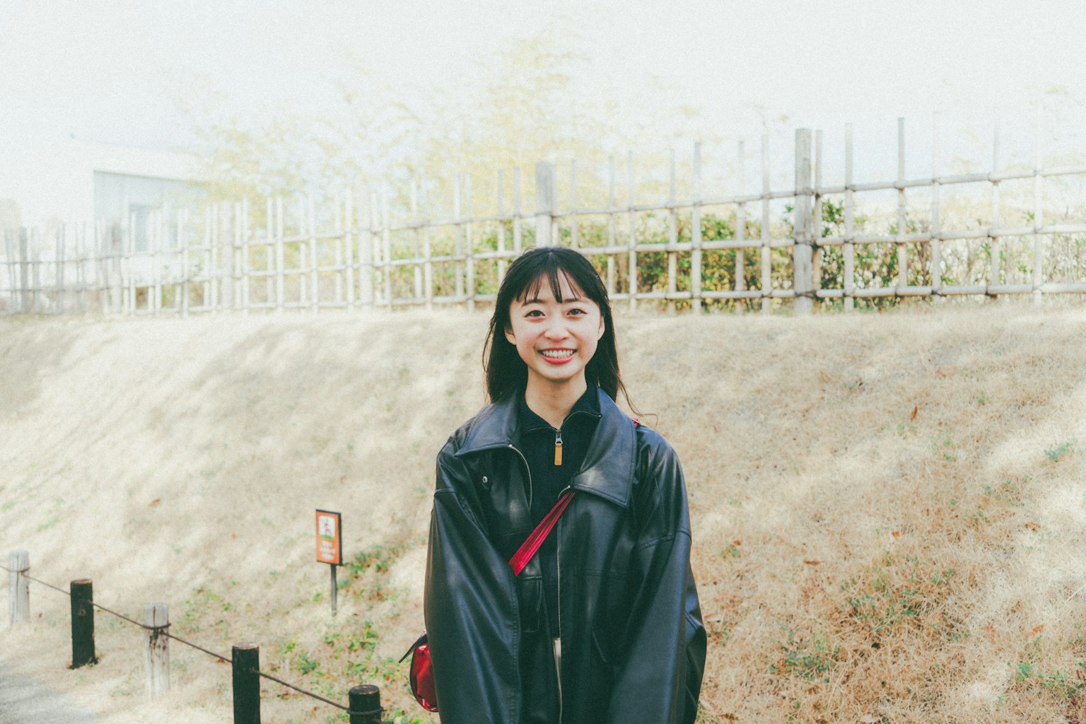 웃고 있는 여성의 파란 재킷이 있는 배경에 녹색 식물이 있다