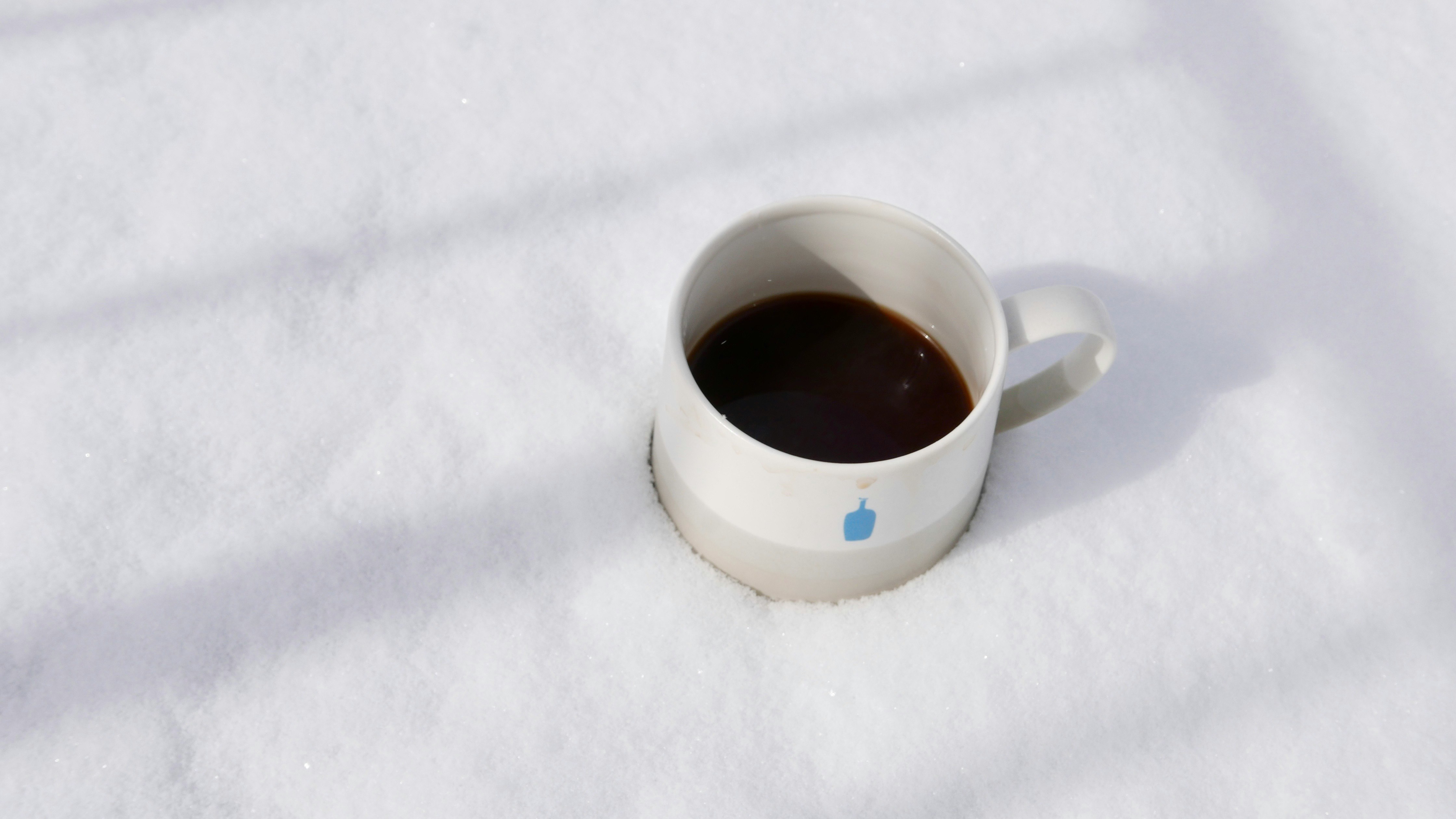 雪の上に置かれたマグカップのコーヒー