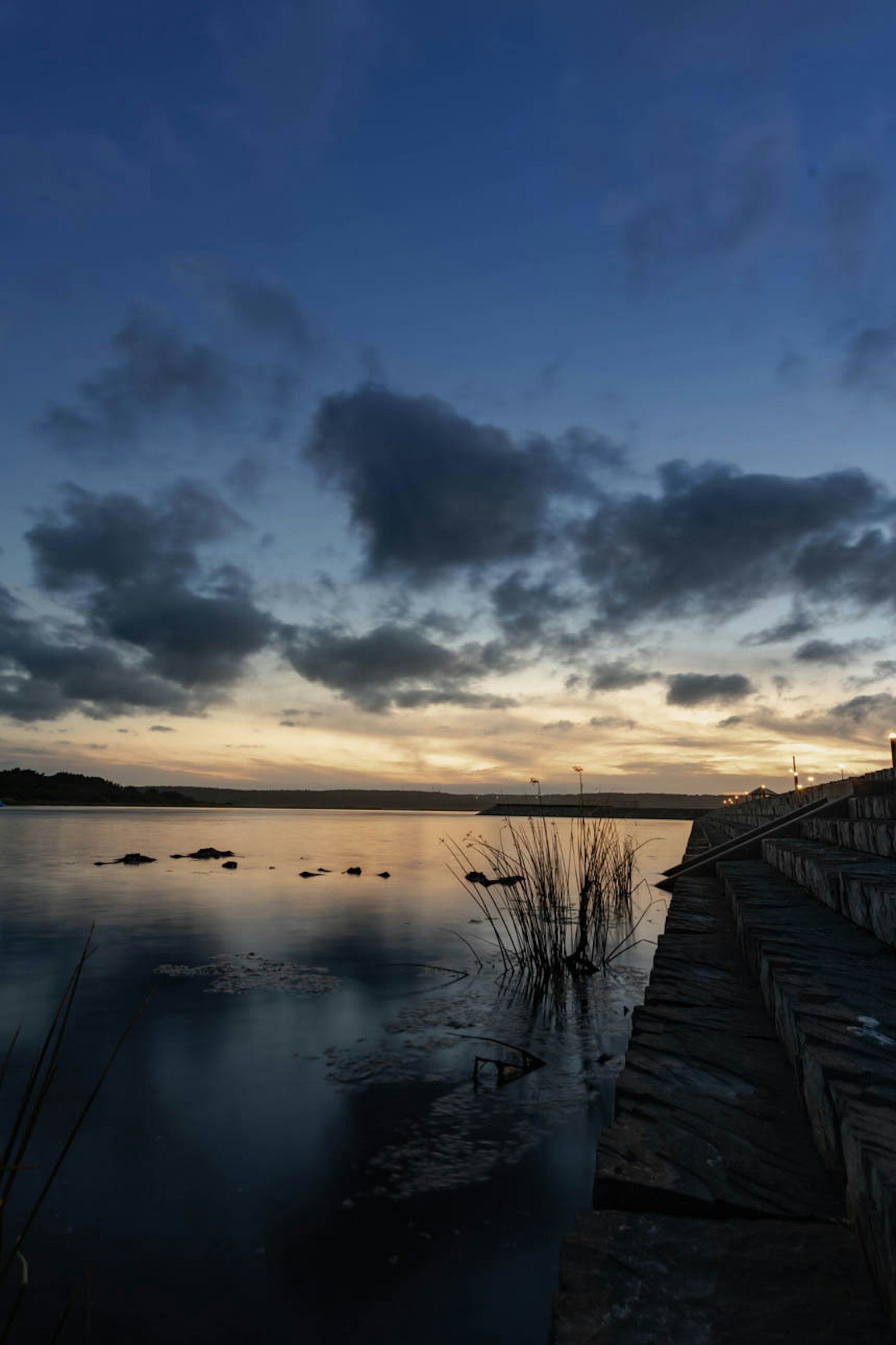 Scena di tramonto sereno al lago con cielo nuvoloso