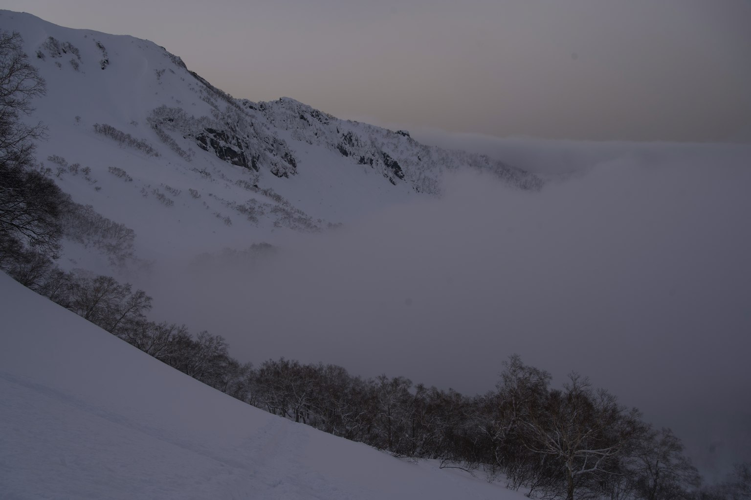 Paisaje tranquilo de montañas cubiertas de nieve y un valle envuelto en niebla
