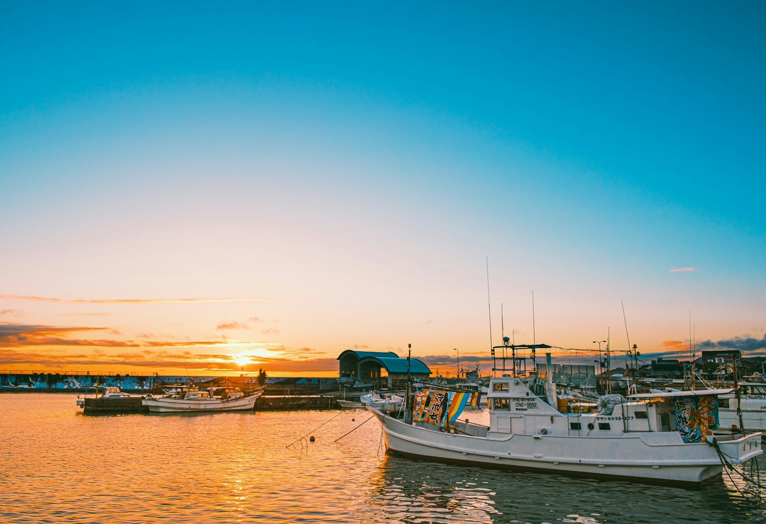 Sunset over the sea with white boats docked at the harbor