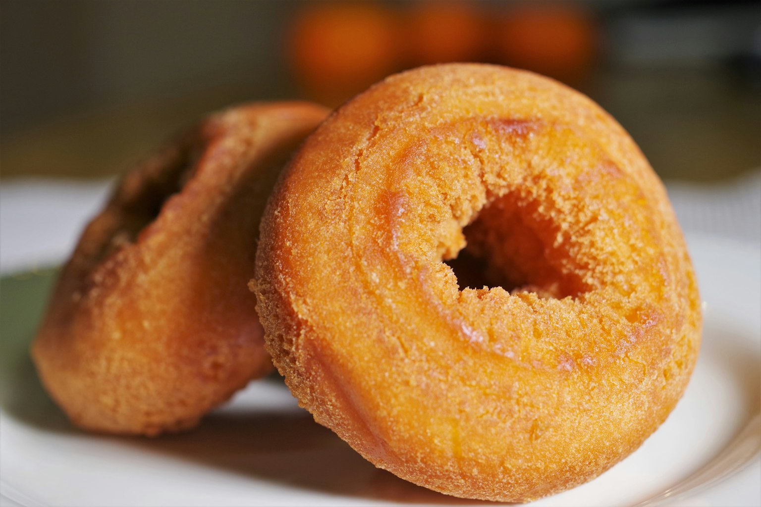 Zwei köstliche orangefarbene Donuts auf einem weißen Teller platziert