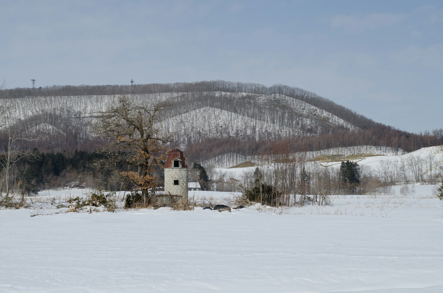 Altes Gebäude in einer verschneiten Landschaft mit umliegenden Hügeln
