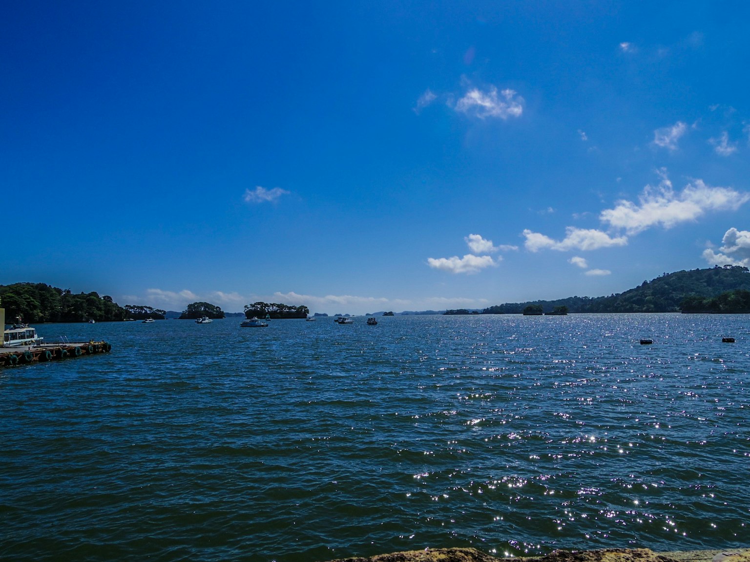 Malersicher Blick auf einen blauen Himmel und schimmerndes Wasser mit Booten und Inseln
