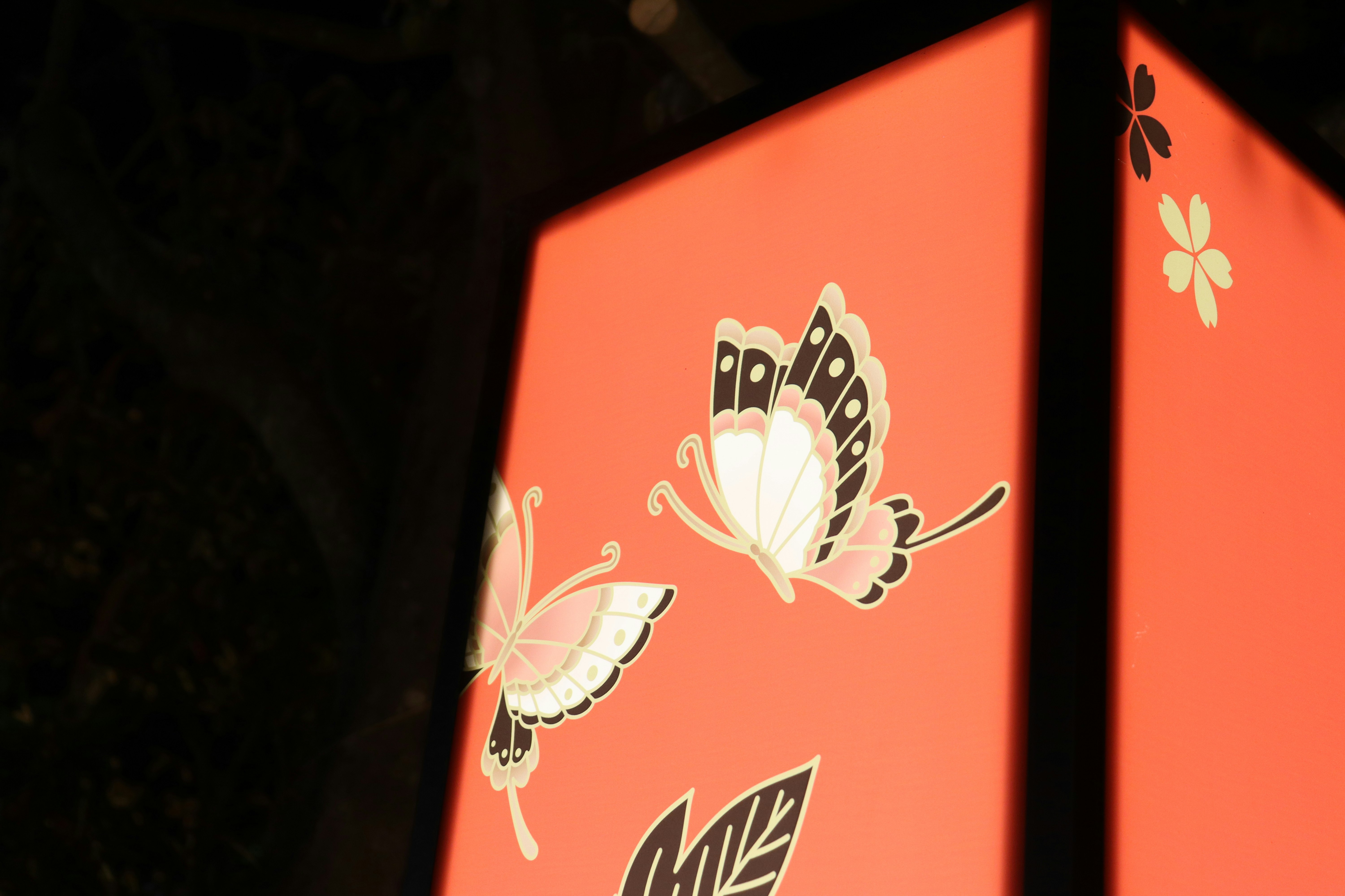 オレンジ色の提灯に蝶と花の模様が描かれた夜の街角