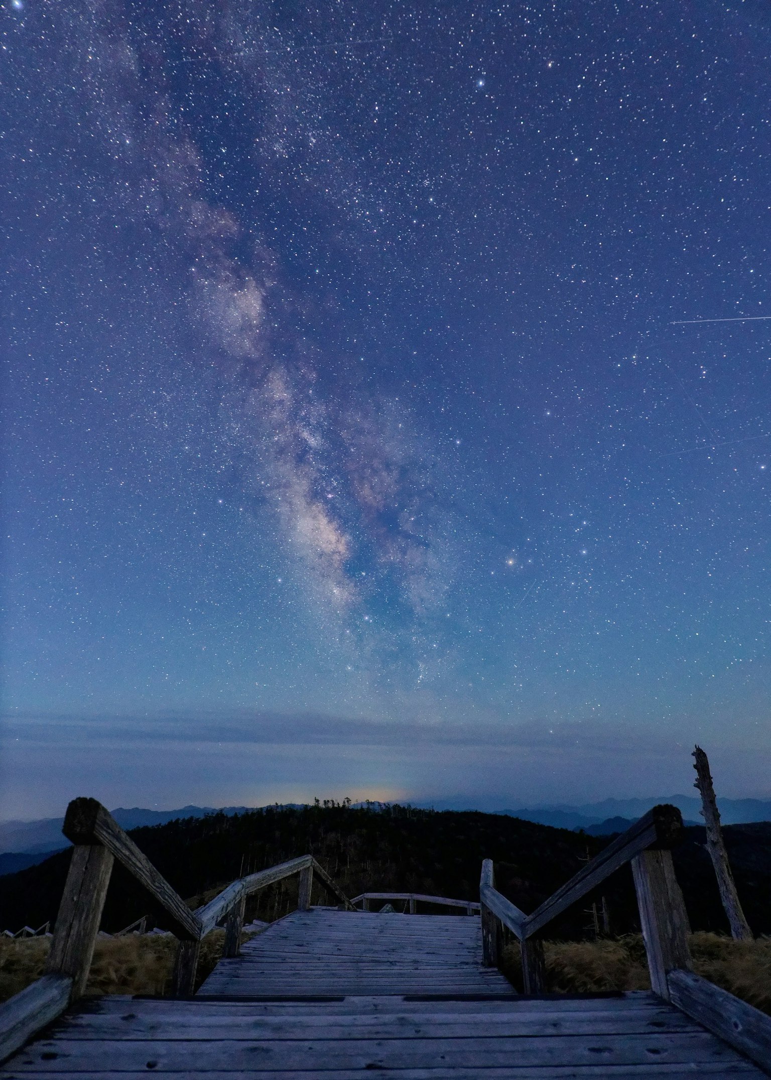 Scale in legno che conducono a una vista mozzafiato della Via Lattea sotto un cielo stellato