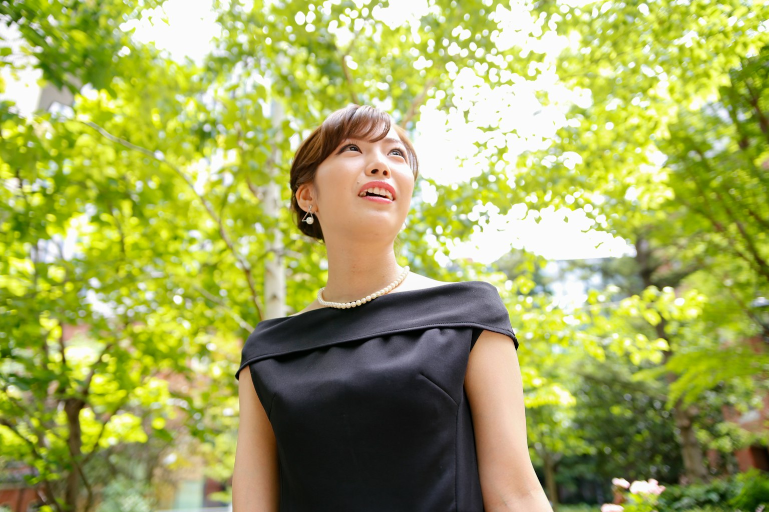 Une femme en robe noire se tenant parmi des arbres verts