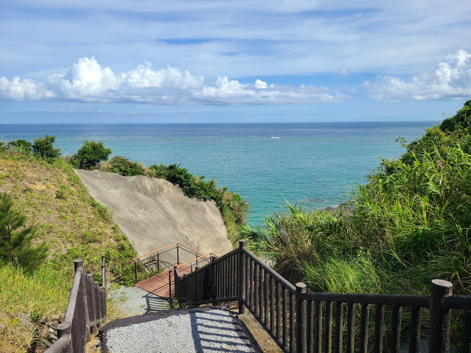 藍色海洋和白色雲彩的風景 有樓梯和木圍欄