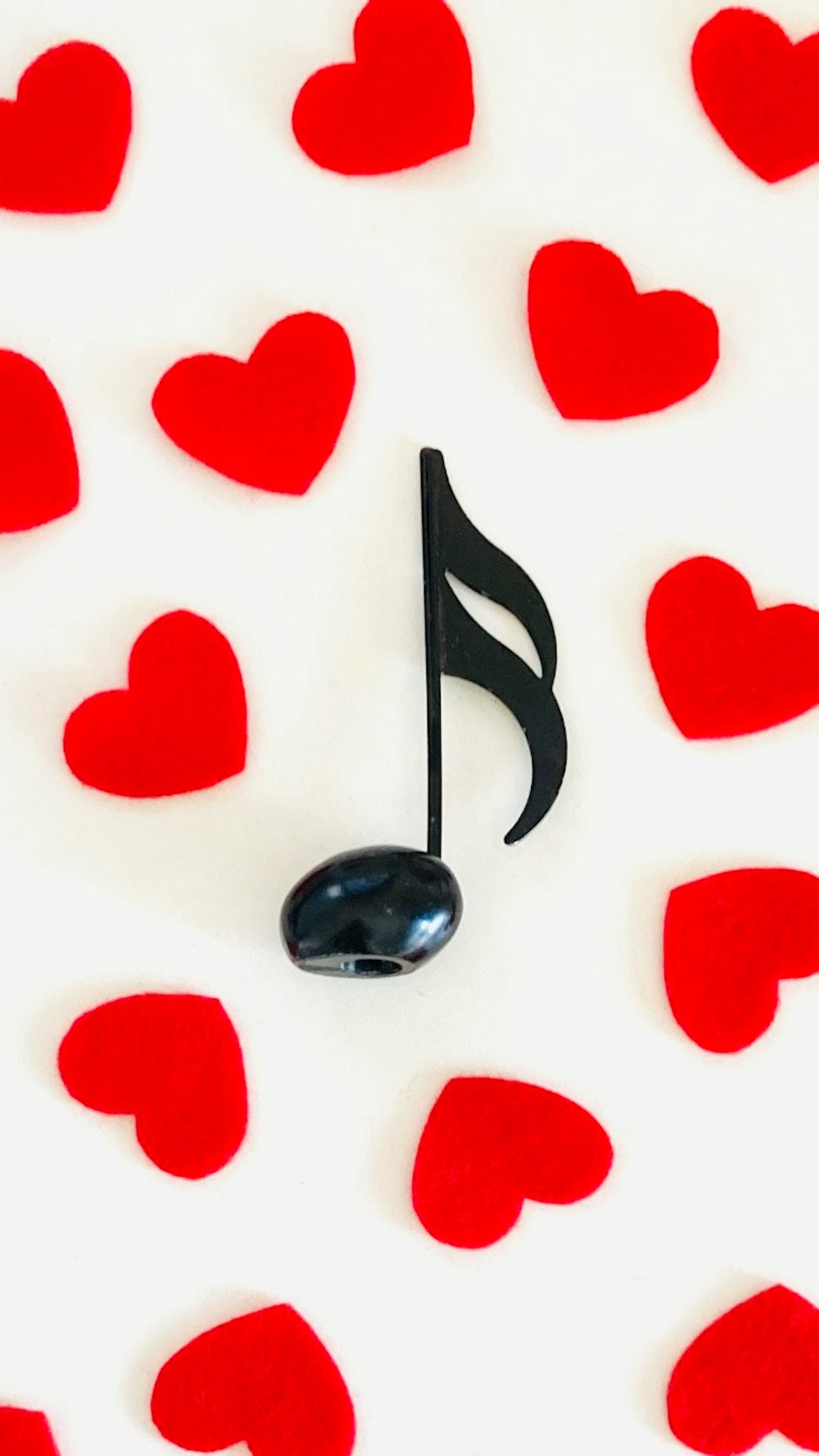 Imagen de una nota musical negra rodeada de corazones rojos
