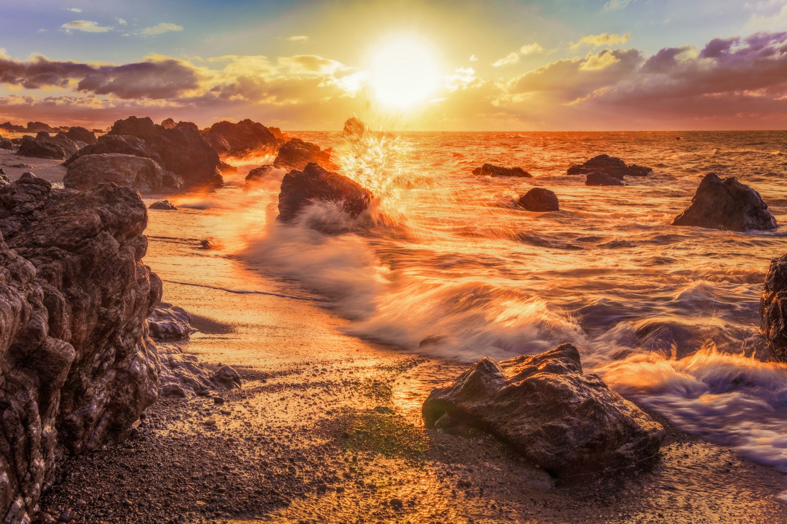 Schöne Strandlandschaft mit Sonnenuntergang über dem Ozean und Wellen an den Felsen
