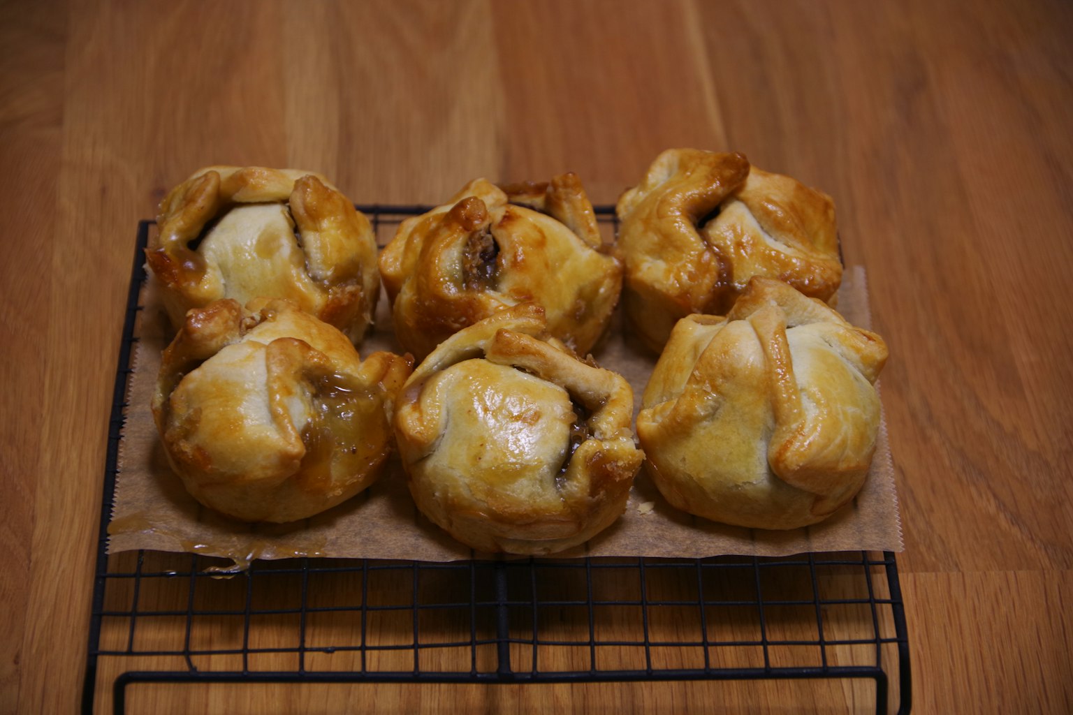 Frisch gebackene Gebäckstücke auf einem Kühlgitter mit goldbrauner Kruste und sichtbarer Füllung
