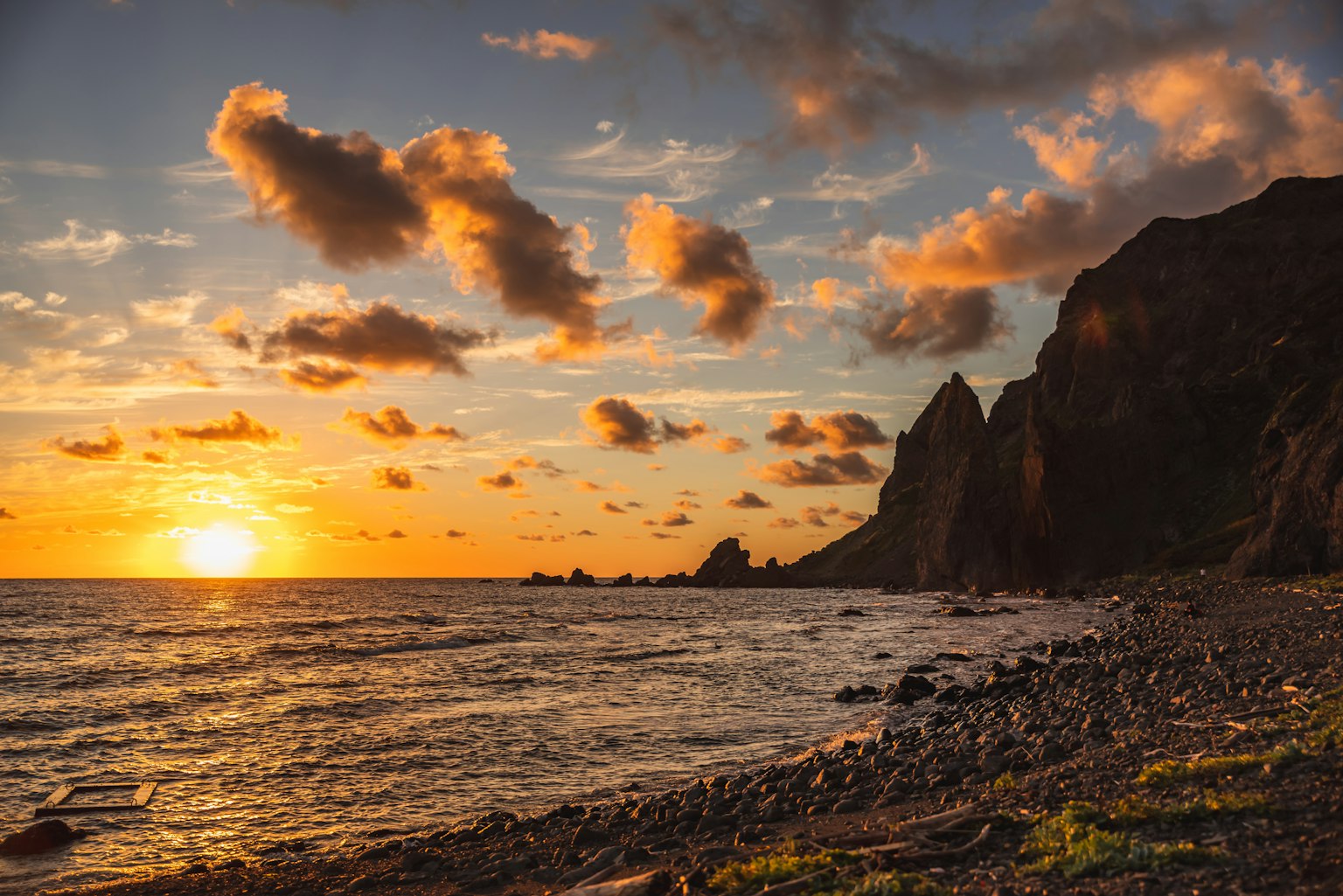 Coucher de soleil pittoresque sur l'océan avec une côte rocheuse et des nuages