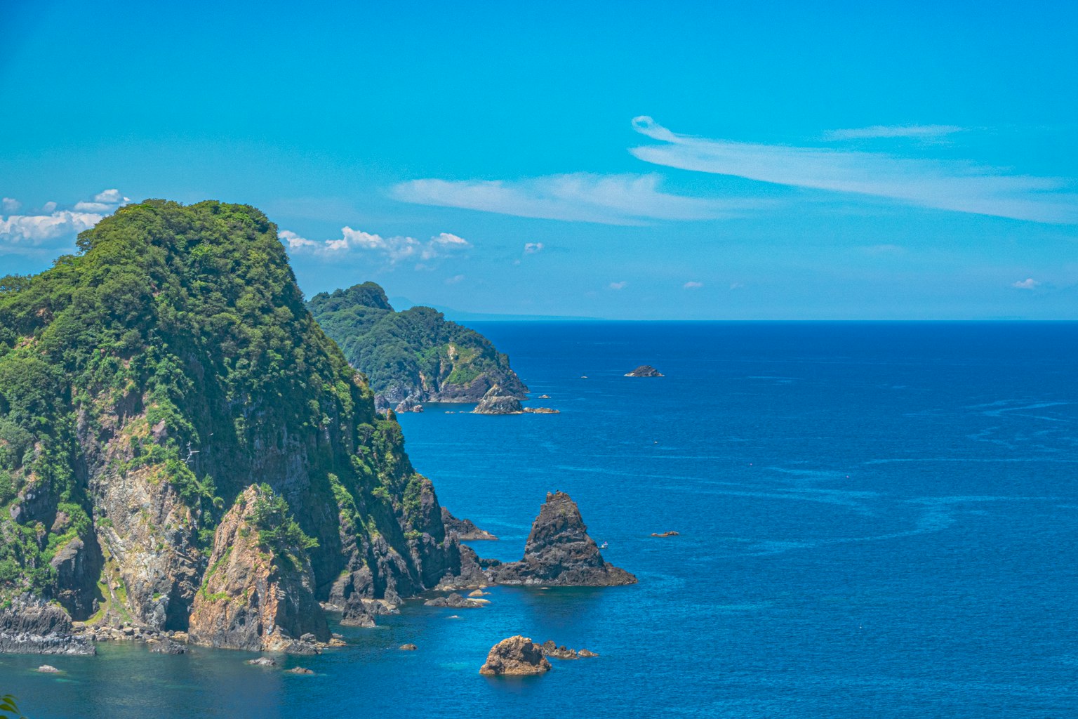 Pemandangan laut biru dan tebing berbatu hijau
