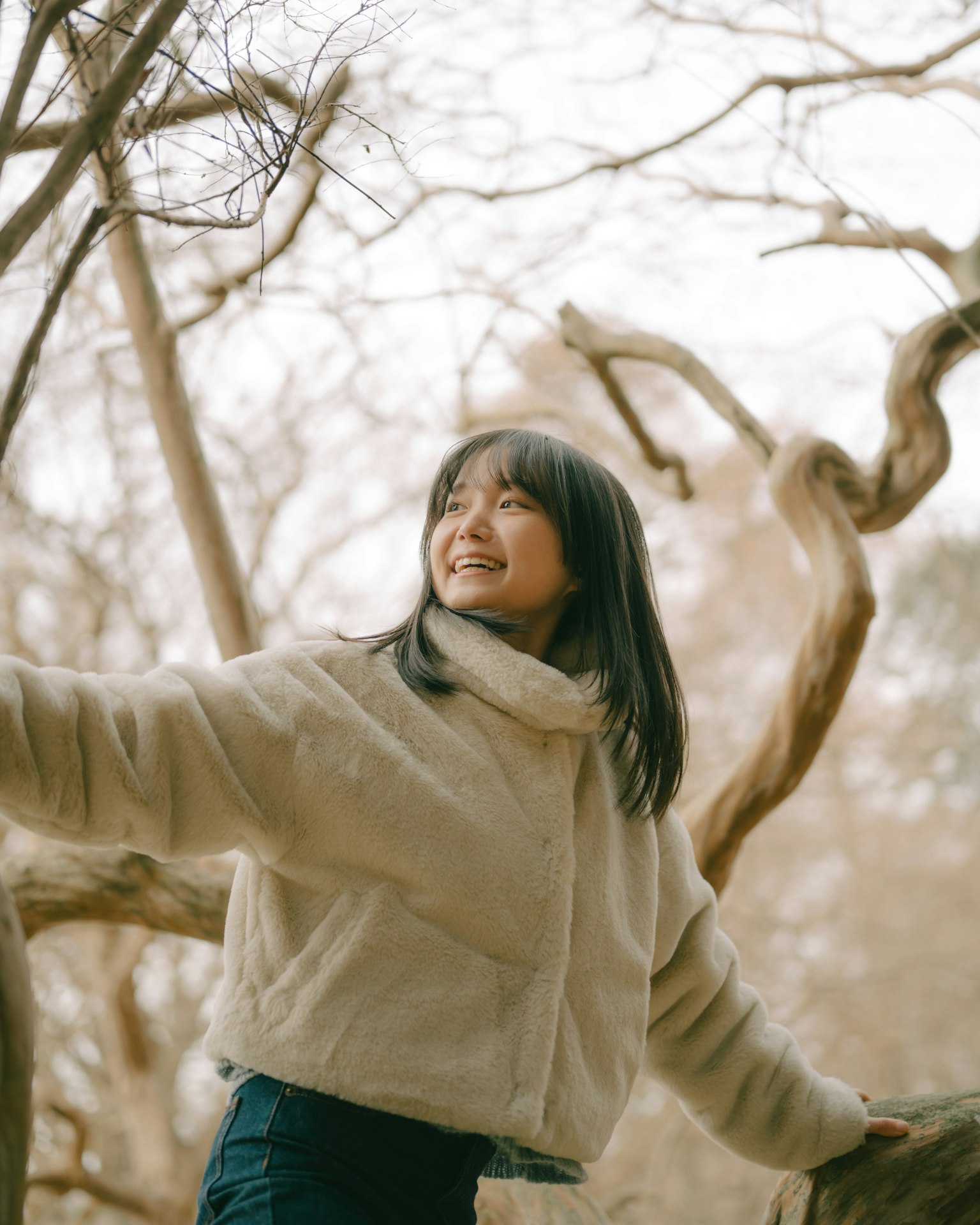 在樹木間微笑的女孩的暖色調照片