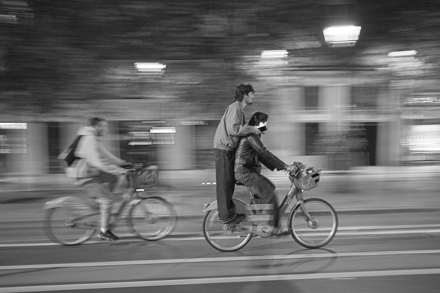 Due persone in bicicletta in una città di notte con sfocatura in movimento