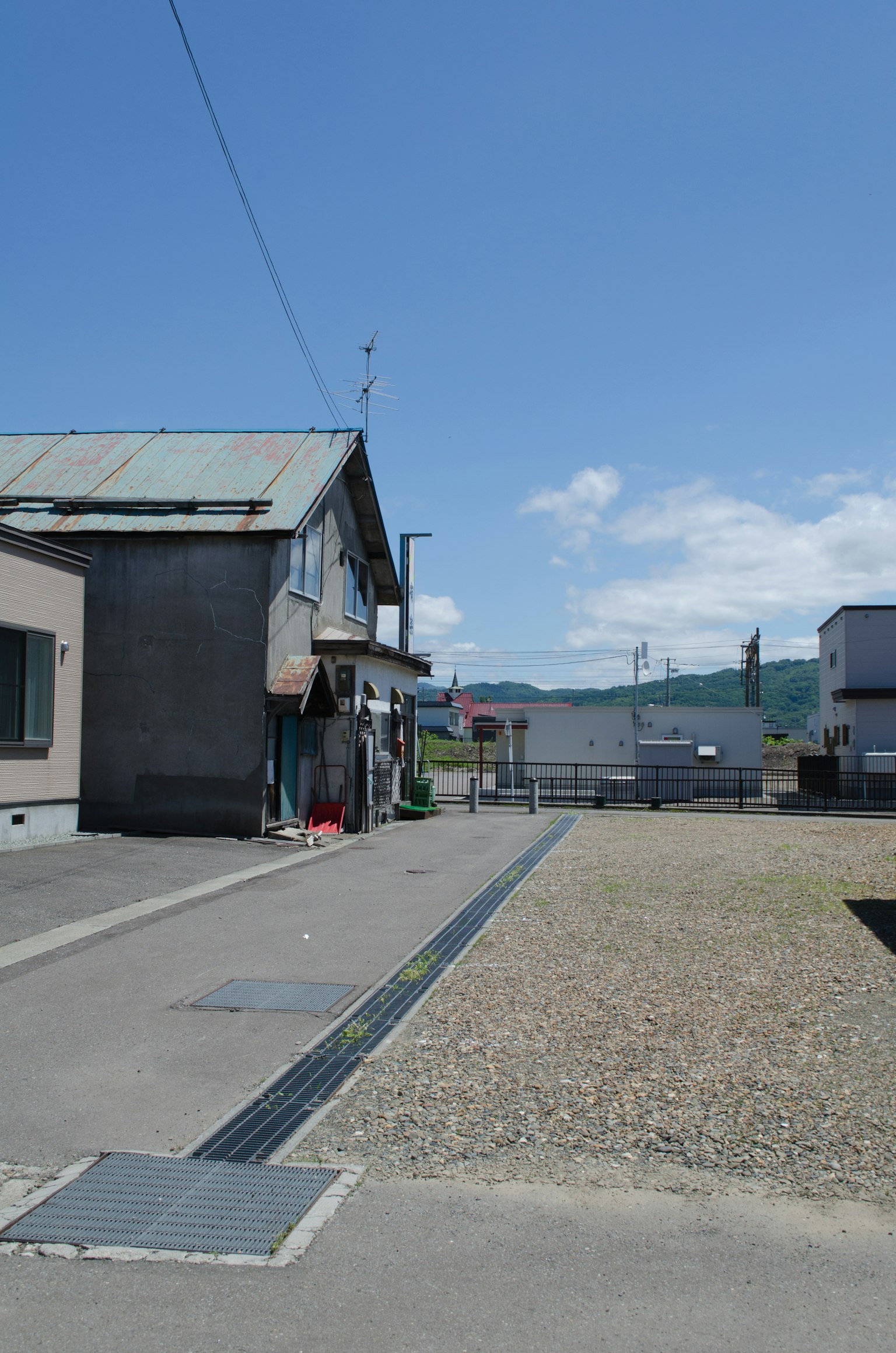 Paesaggio con un vecchio edificio e un ampio lotto vuoto sotto un cielo blu