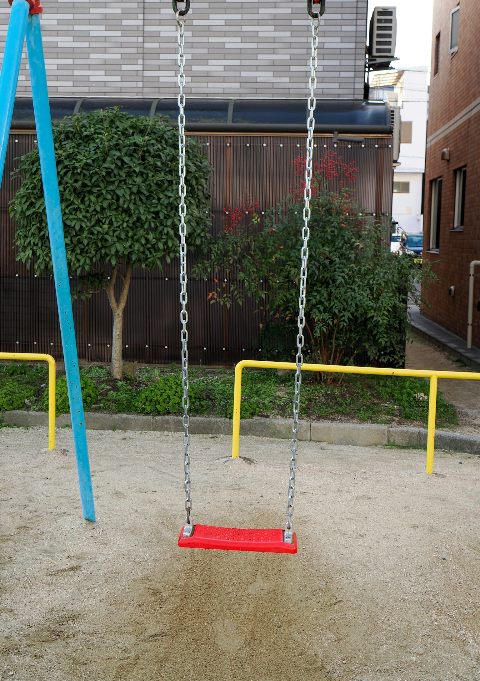 Aire de jeux simple avec une balançoire rouge et un poteau de soutien bleu