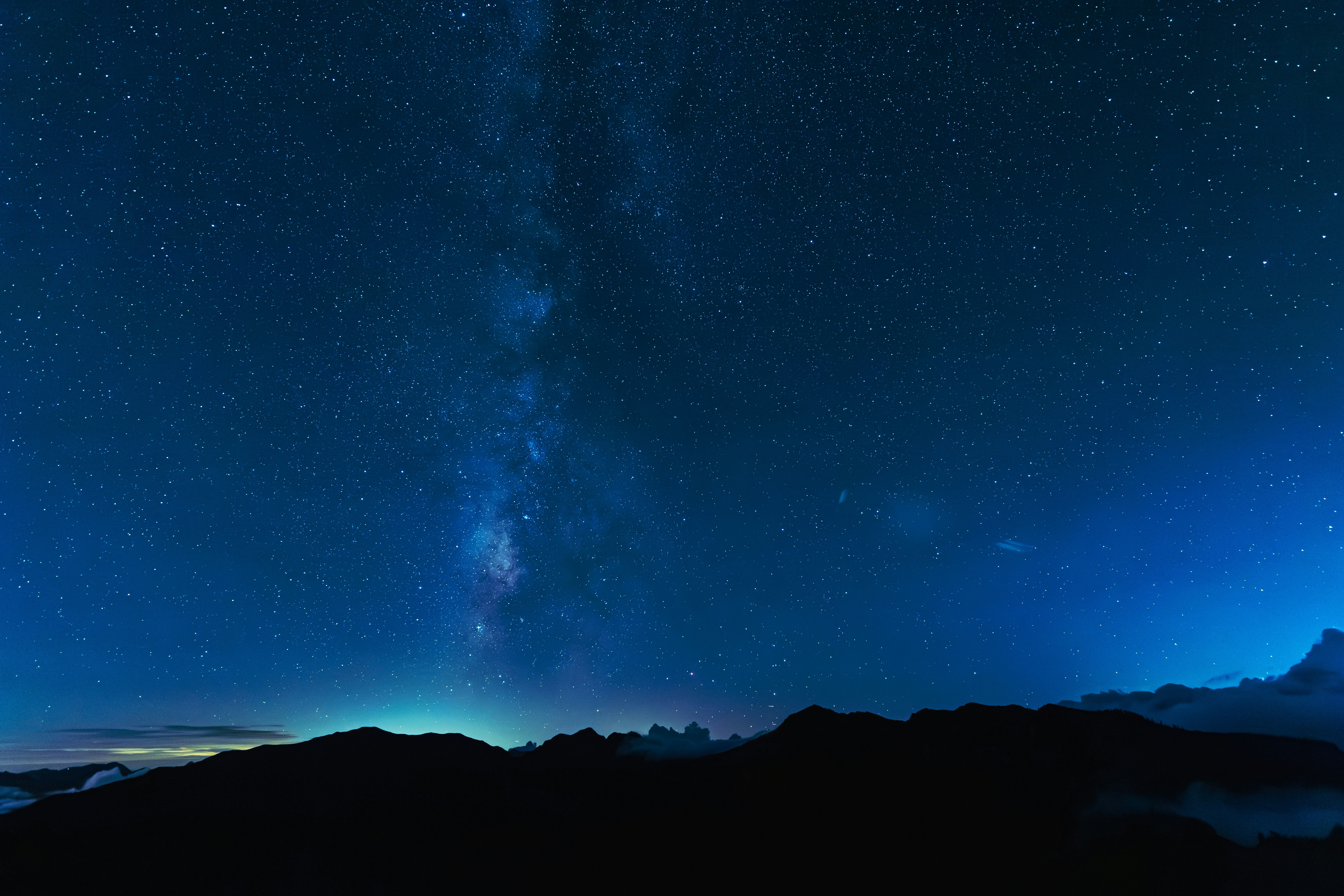 夜空に広がる星と天の川の見える山並みのシルエット