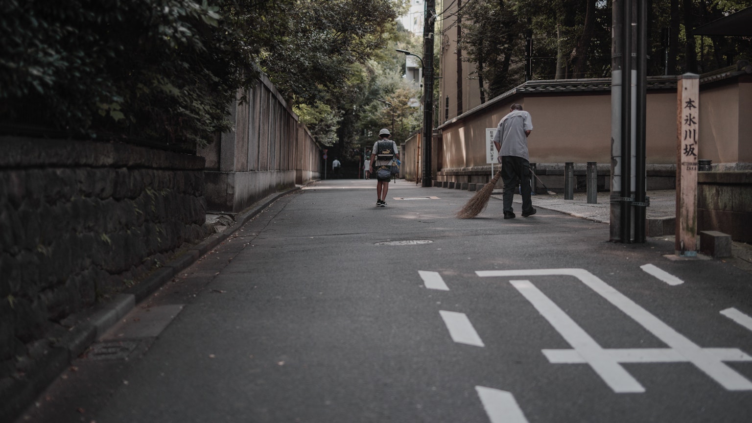 Scene of a quiet street with a person walking and another on a bicycle
