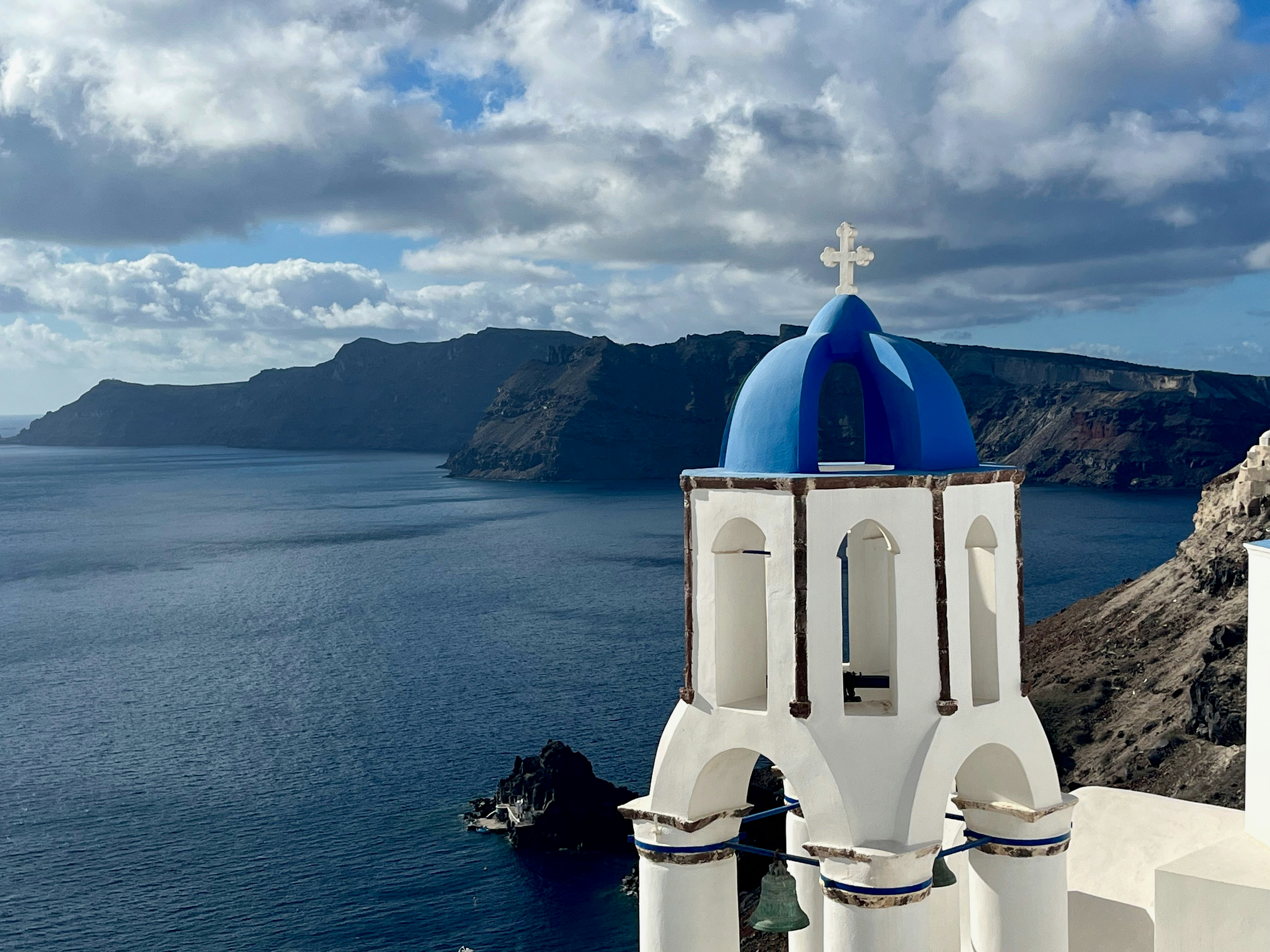 Blue-domed church in Oia, Santorini overlooking the Aegean Sea