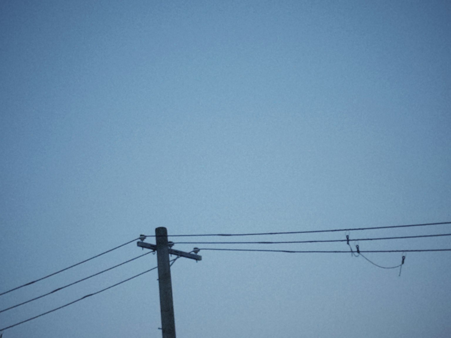 藍天背景下的電線桿和電線的簡單視圖