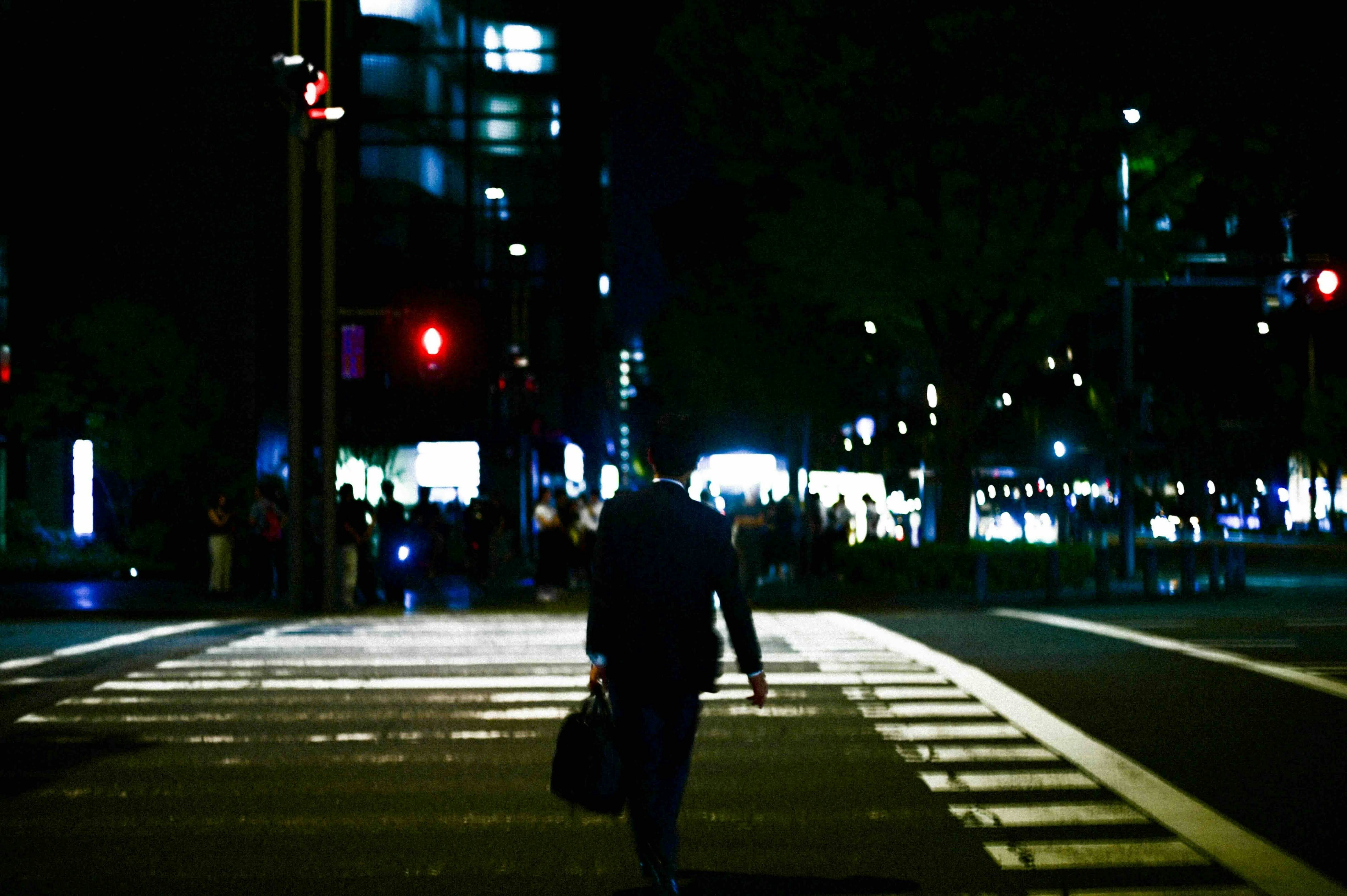 夜の横断歩道を歩く人と街のネオンの光