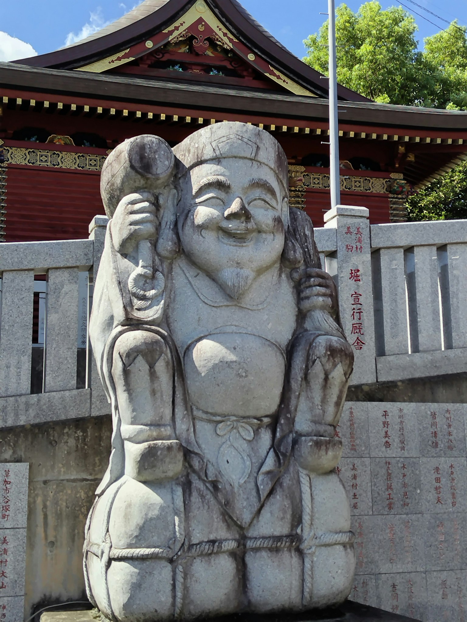 微笑石像正搬运重物，背景为神社