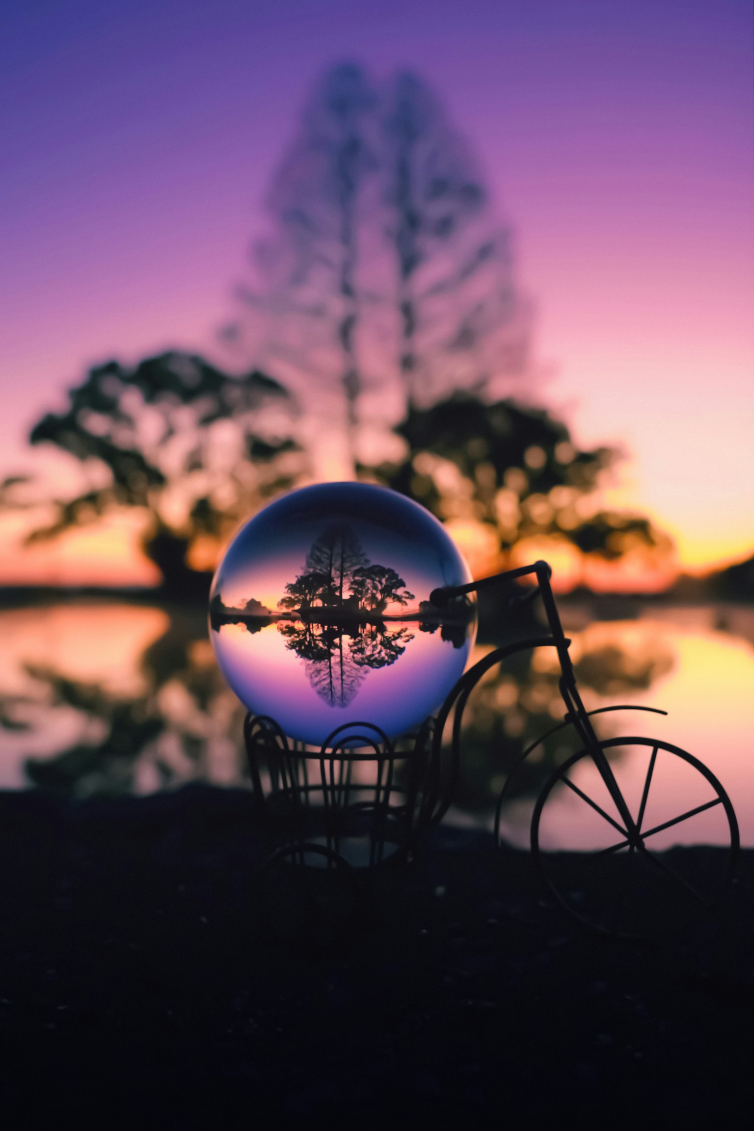 Une boule en cristal placée dans un panier de vélo avec un fond de coucher de soleil